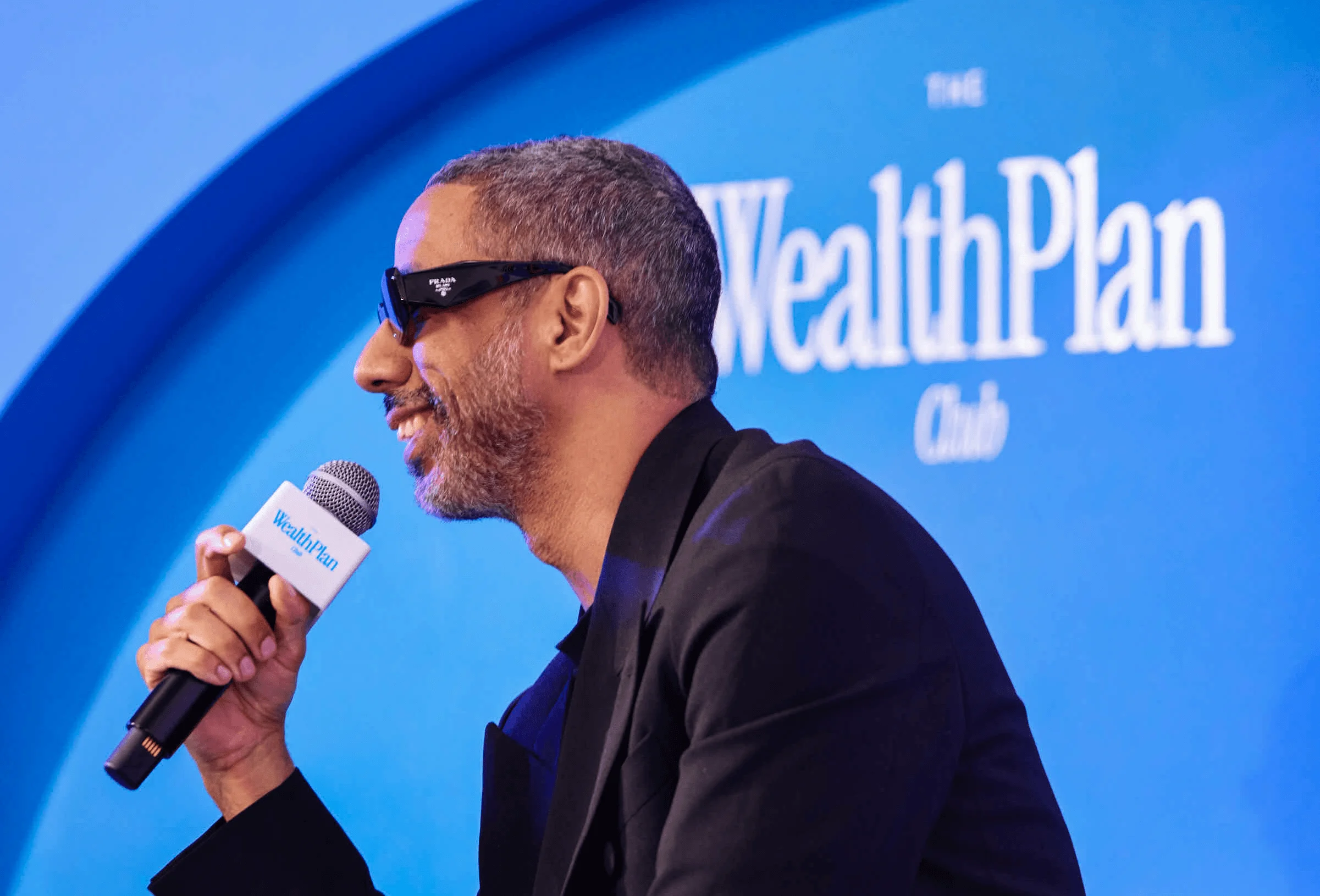 Ryan Leslie speaking on stage at a WealthPlan Club event.