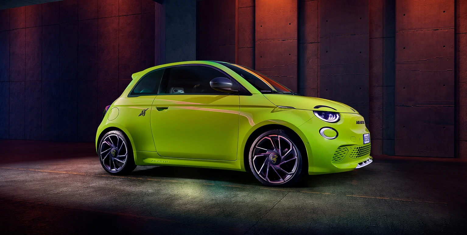 Grüner Abarth 500e vor einer rot beleuchteten Betonwand