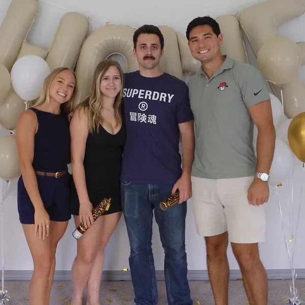 The Sumners with two clients in front of balloons at a home celebration.