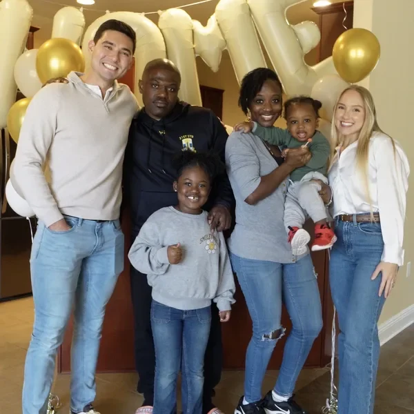 The Sumners with a family and their children in front of gold HOME balloons.