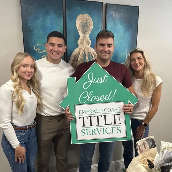 Derrick and Emily with clients holding a green Just Closed sign.
