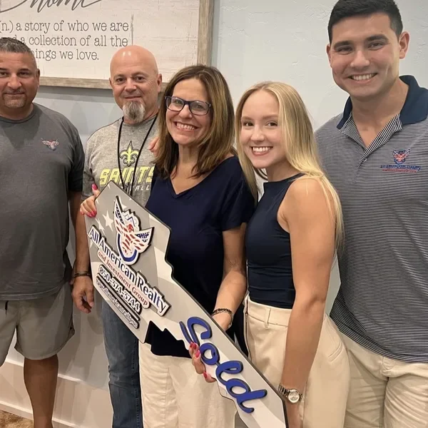 Derrick and Emily with three clients holding a Sold key sign.