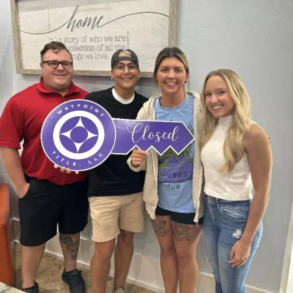 Emily with three clients holding a Closed key sign on closing day.
