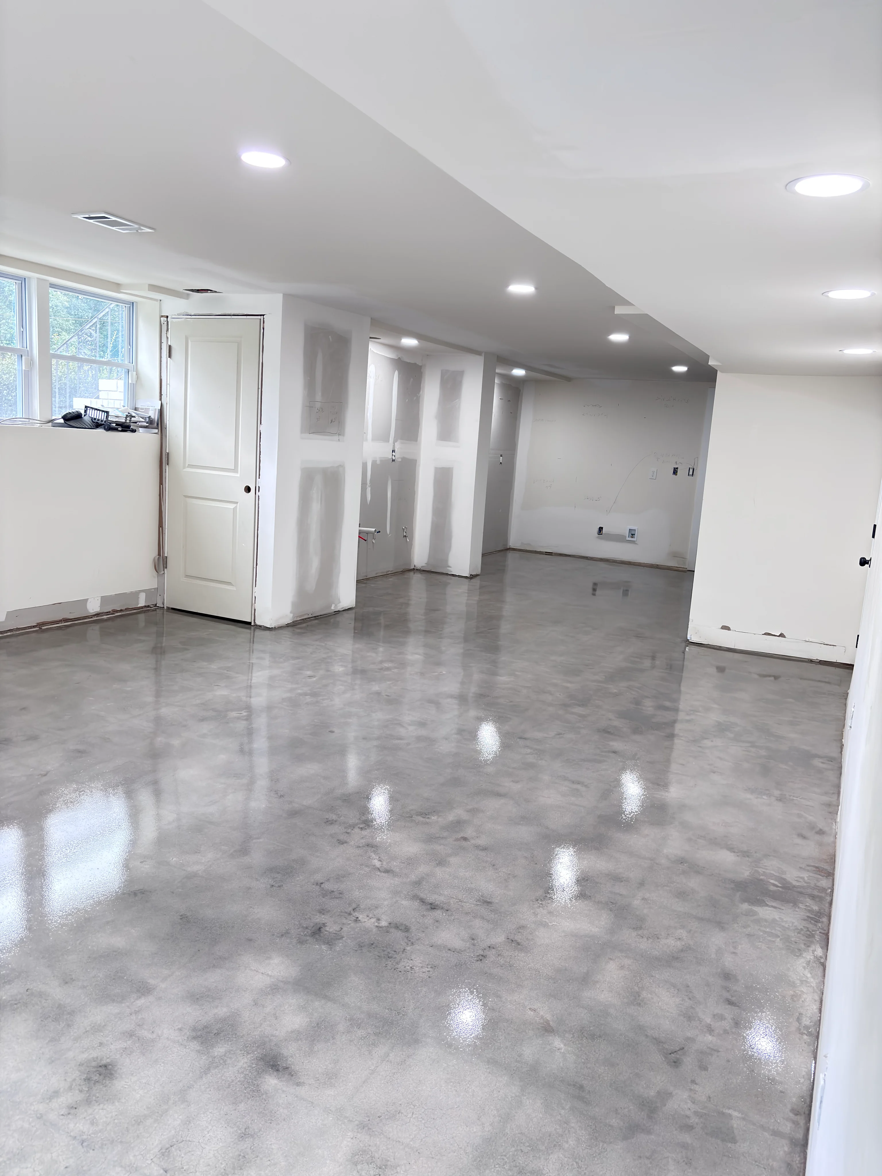 Glossy gray concrete floor in an unfinished residential basement