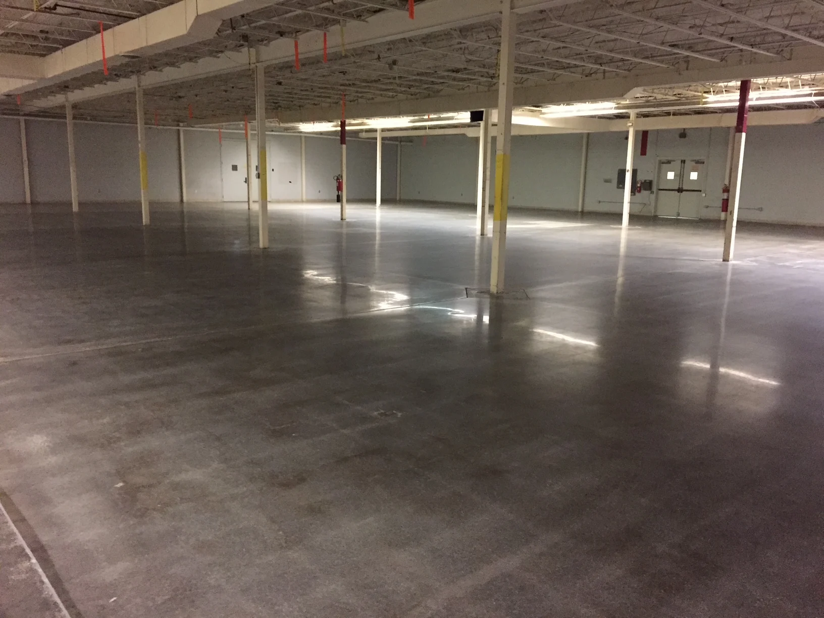 Reflective gray concrete floor in an empty industrial building with support columns