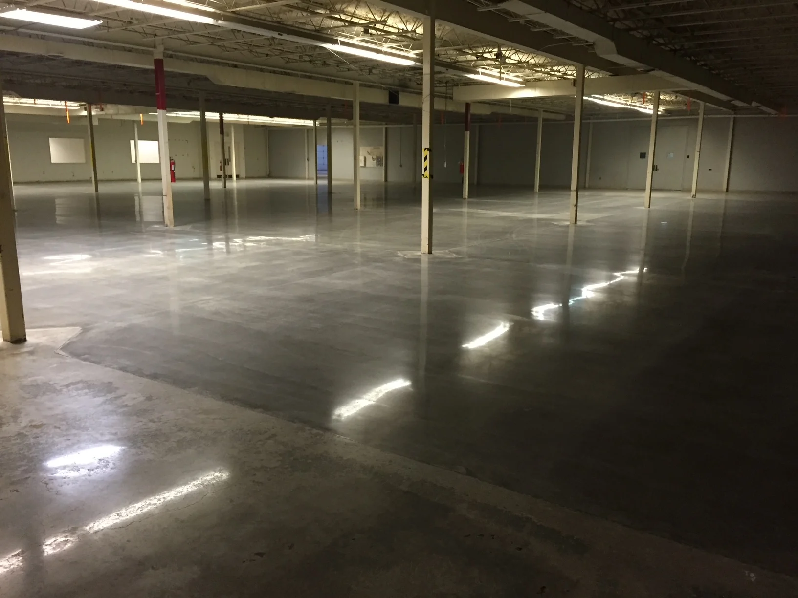 Reflective gray concrete floor in an open industrial interior with support columns