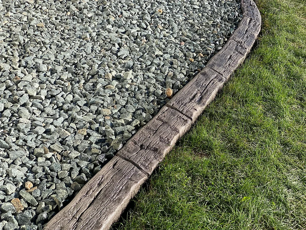 Concrete landscape edging between gravel and grass