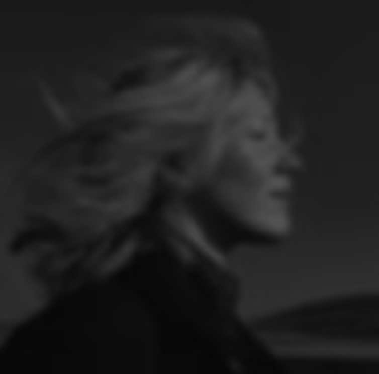 Blurred grayscale side profile of a person with windblown hair against a dark background.