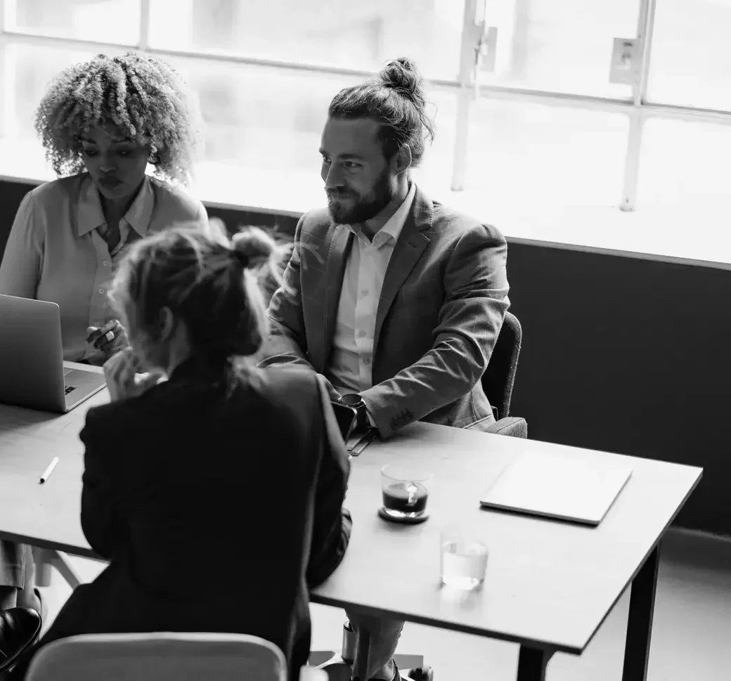 A diverse hiring team discussing talent decisions around a conference table.