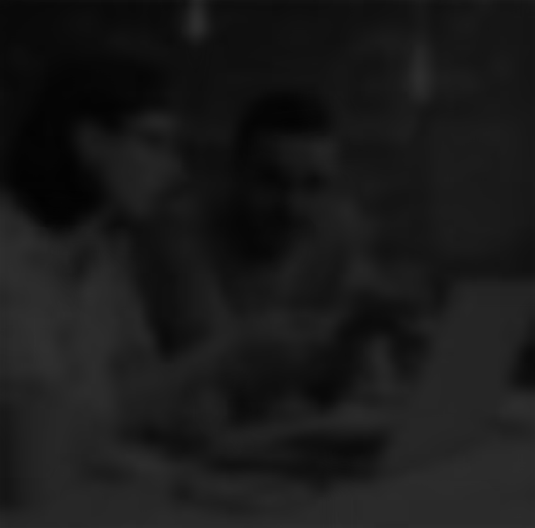 Two people sitting at a table, looking at a smartphone together in a dimly lit room.
