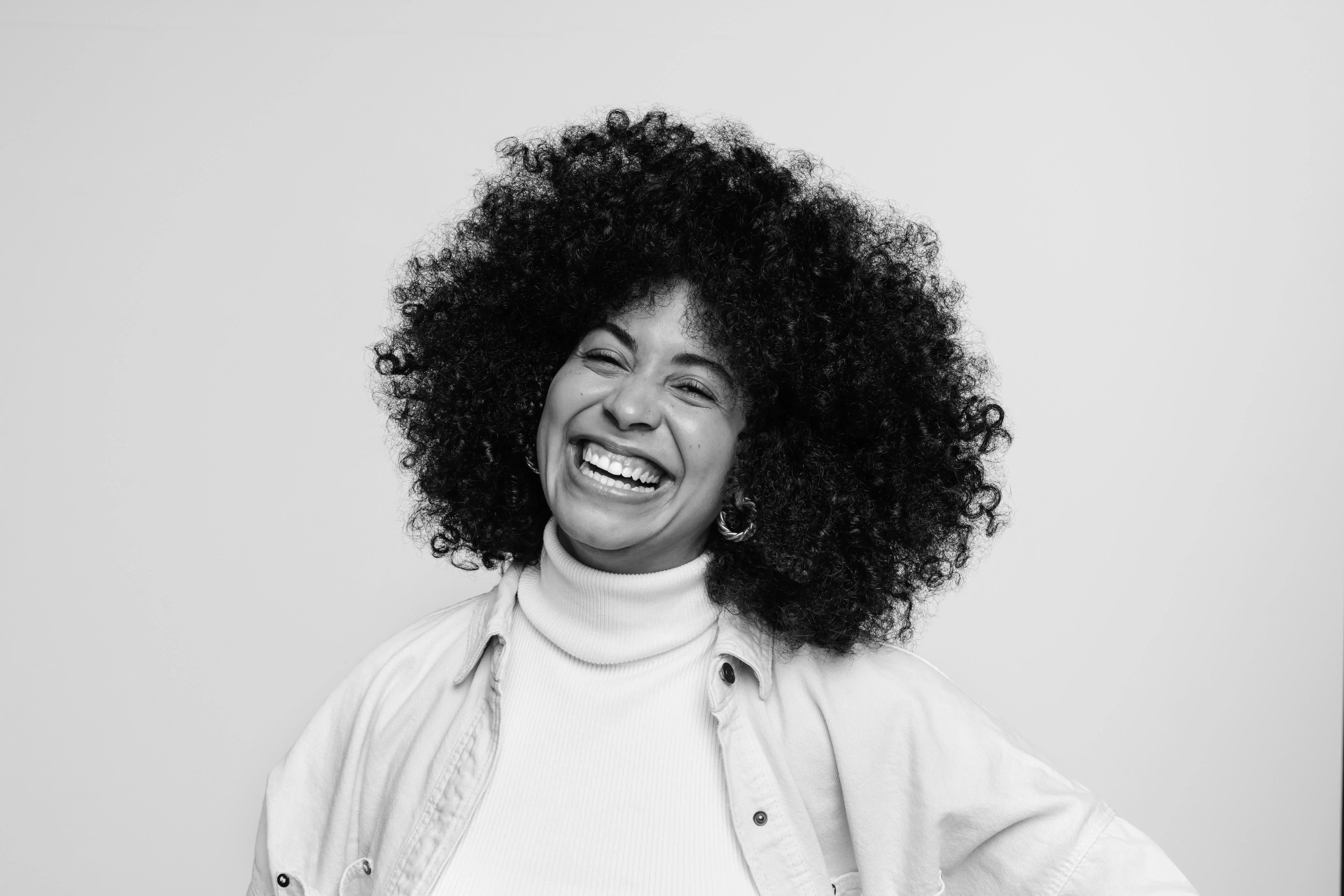 Black-and-white portrait of a talent leader laughing against a clean studio background.