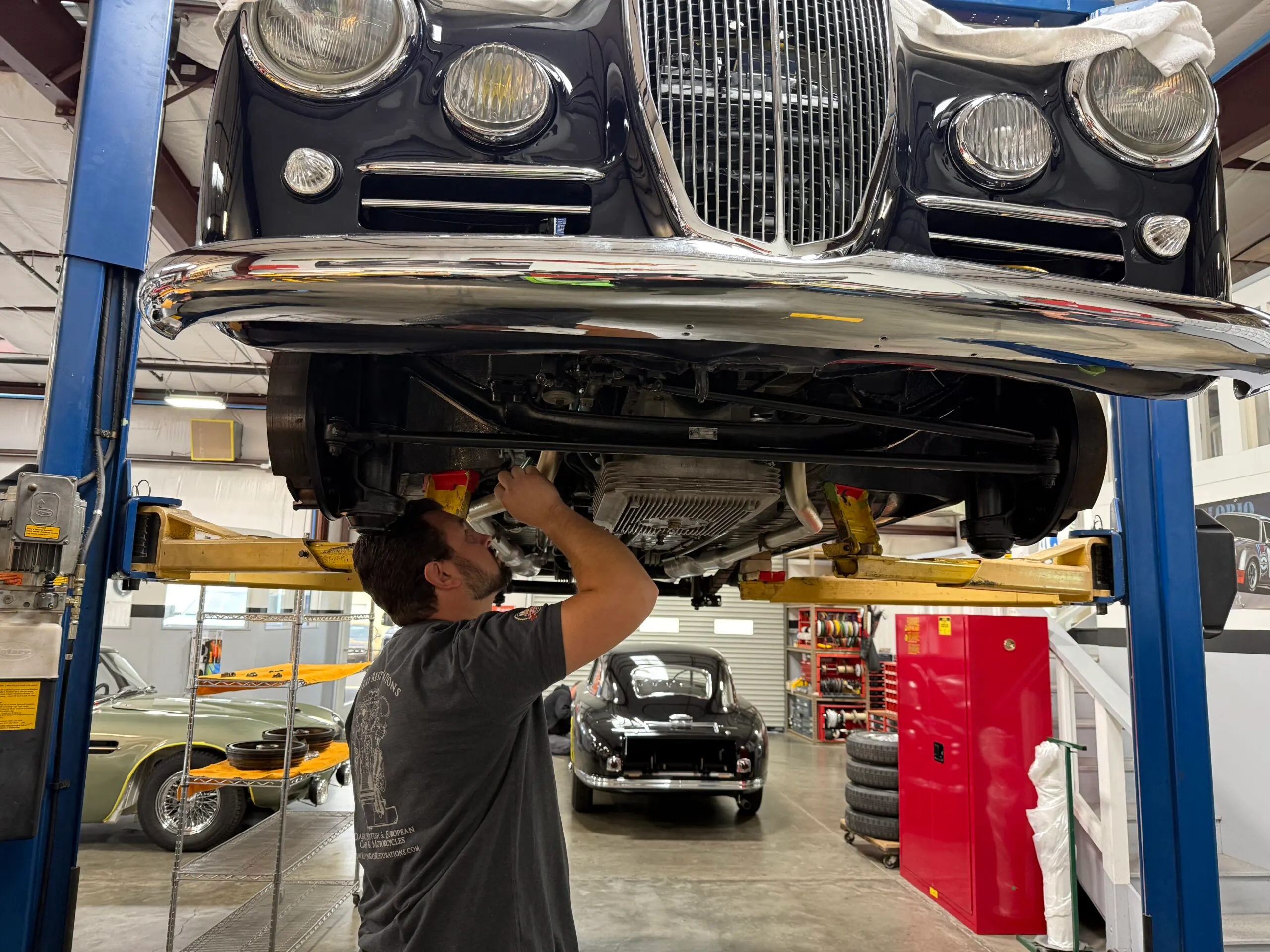 Kevin Kay Restorations technician inspecting a collector car on a lift