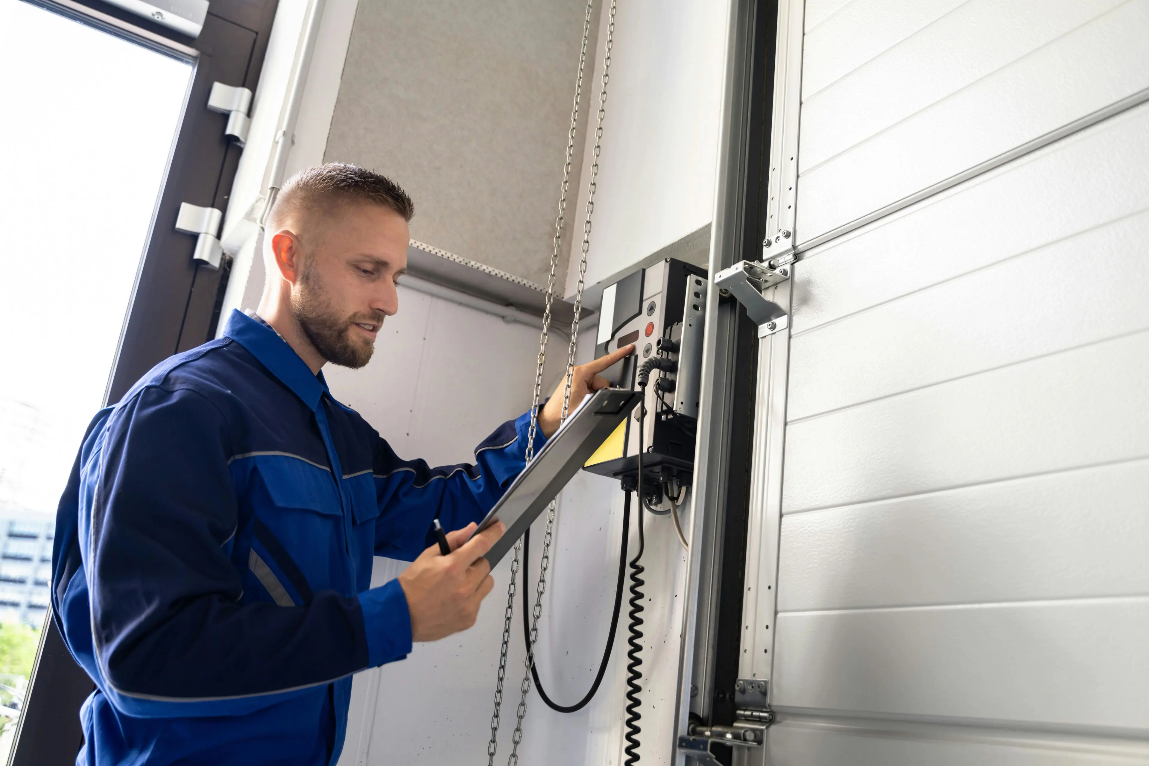 Technician inspecting a commercial garage door opener with a tablet