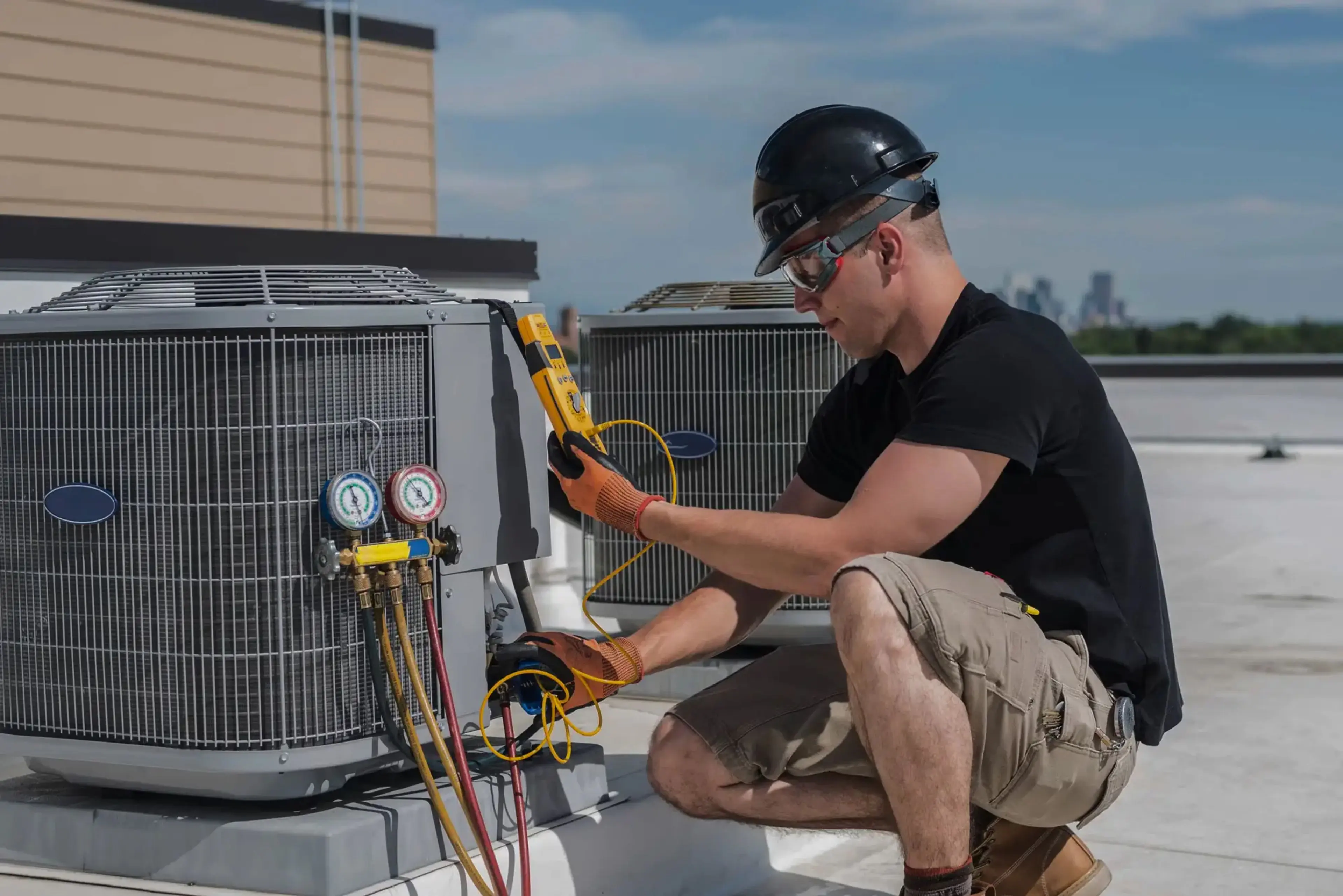HVAC technician using gauges to service a rooftop air-conditioning unit