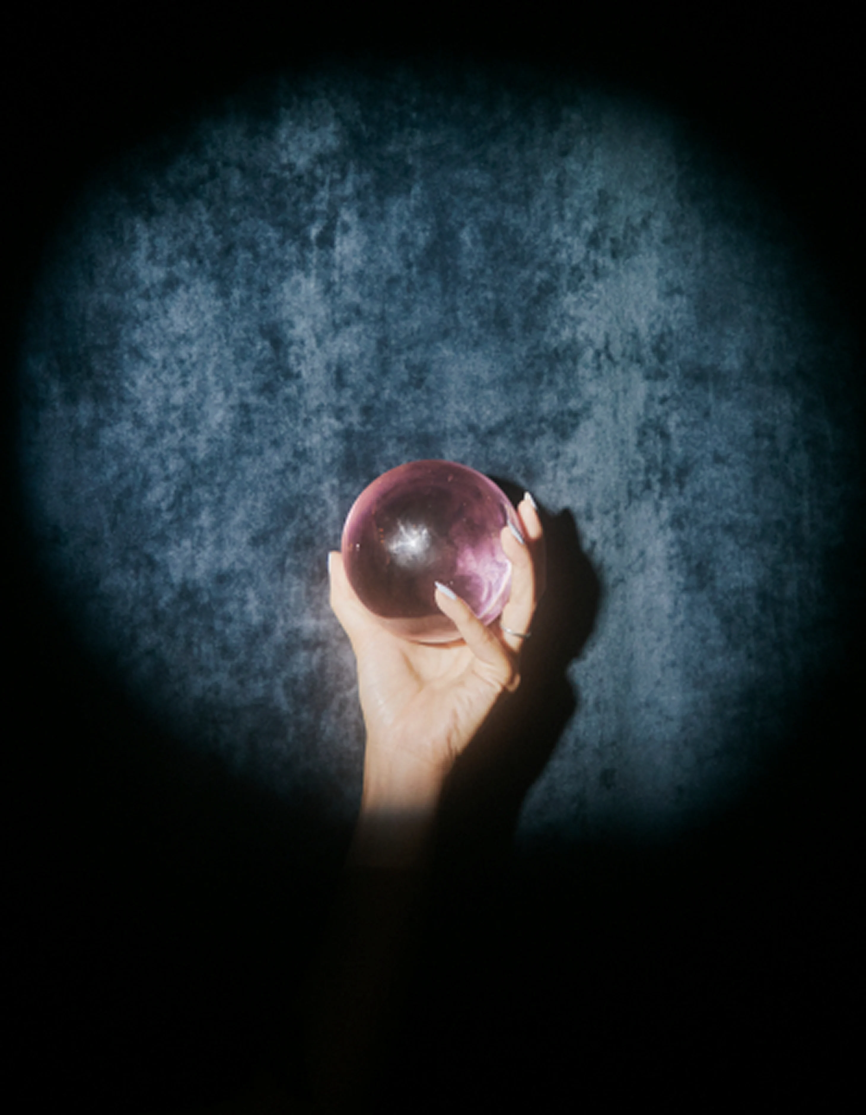 A hand holding a glowing crystal orb with changing company logos