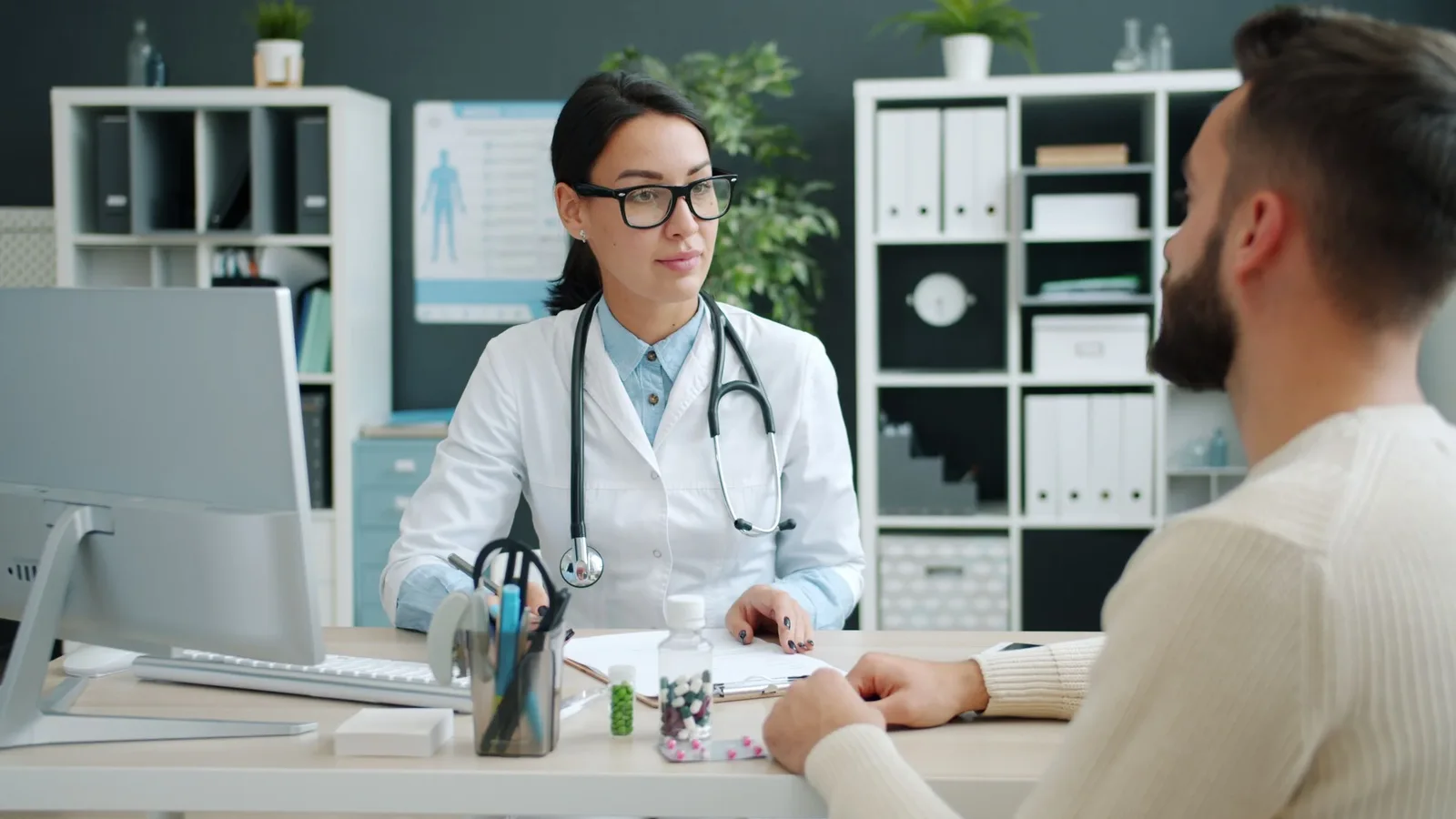 A physician listening to an adult patient during a private clinical consultation