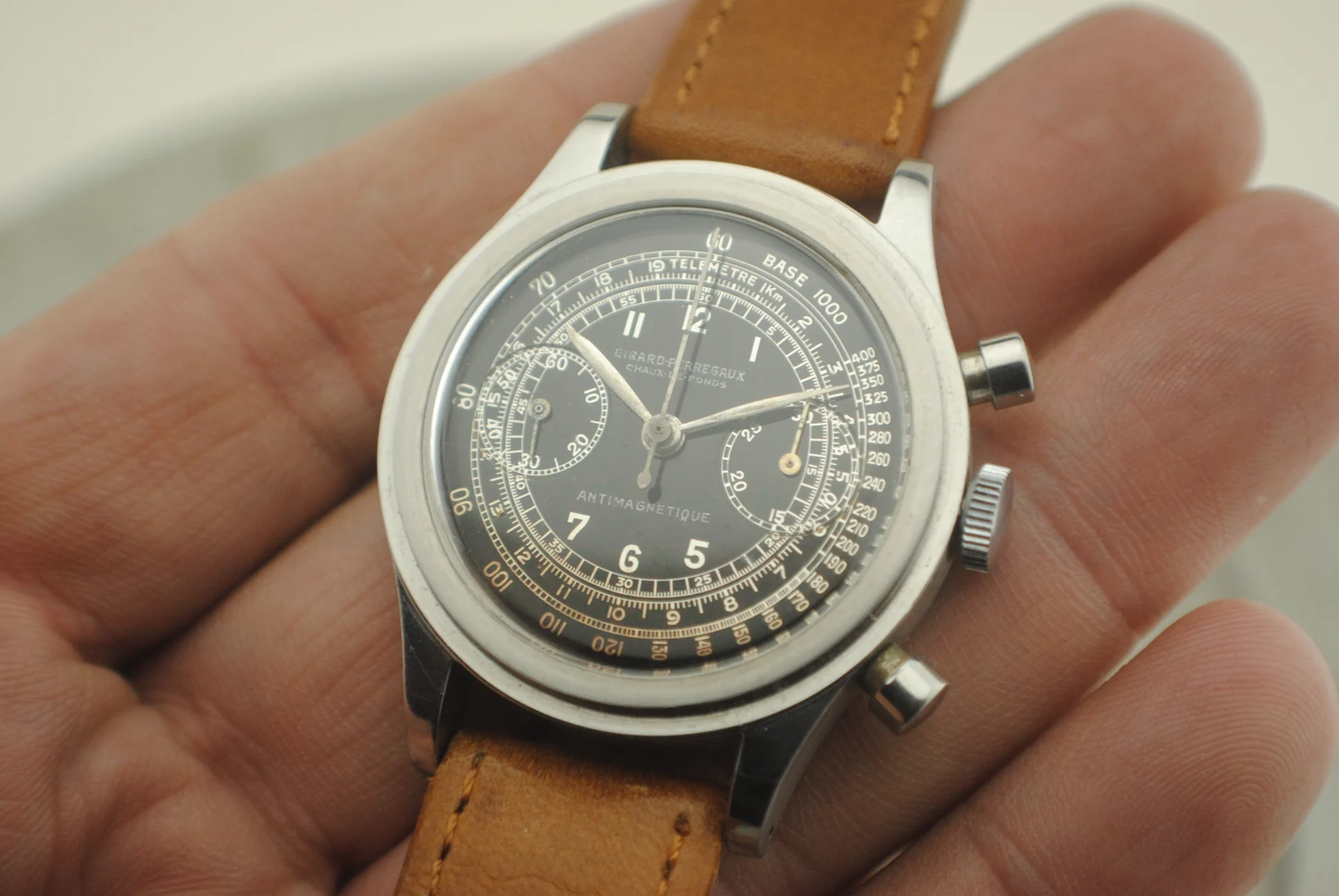 Bright crystal-on in-hand view of the Girard-Perregaux chronograph with silver galvanic multi-scale dial