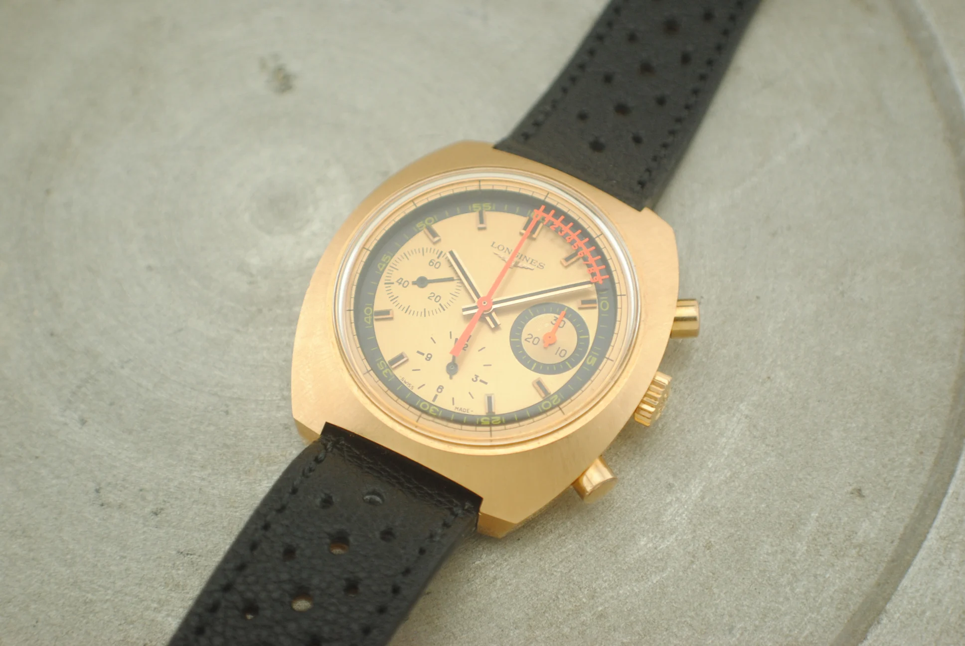 Crystal-on front view of the Longines Nonius rose-gold chronograph on a grey surface