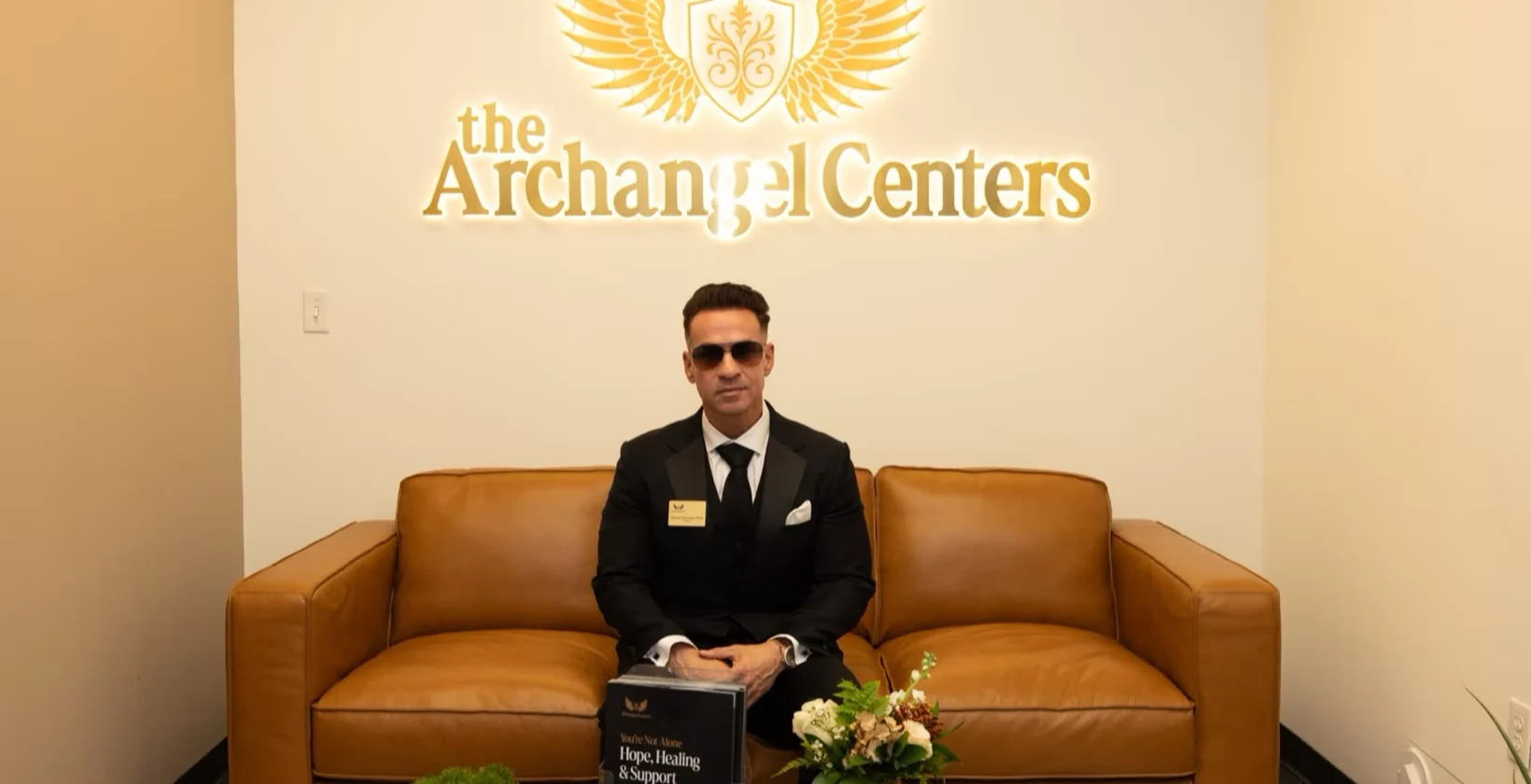 Mike Sorrentino seated in the Archangel Centers lobby beneath the illuminated logo