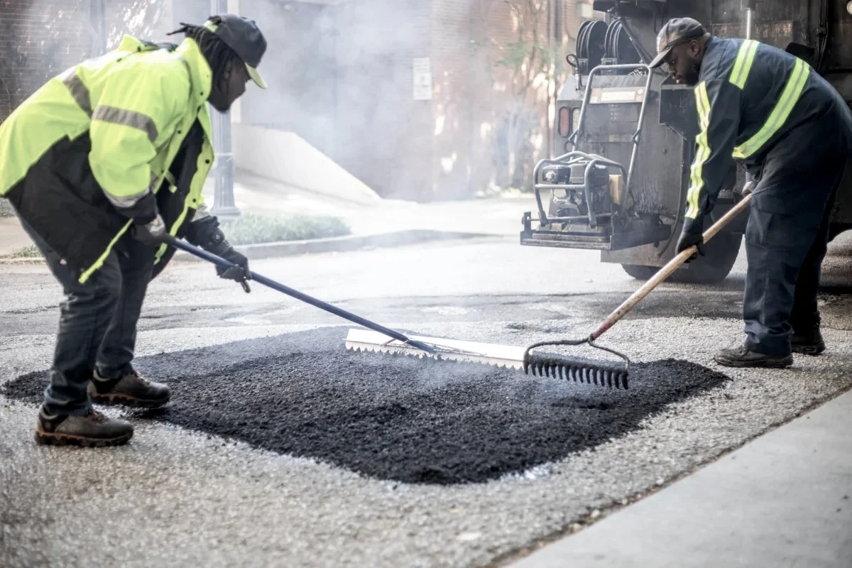 Road crew spreading asphalt to repair a pothole