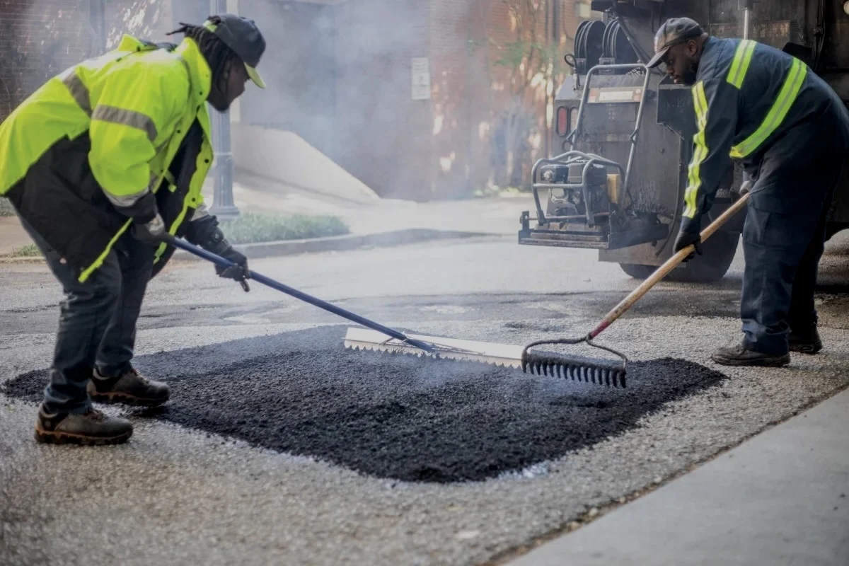 Road crew spreading asphalt to repair a pothole