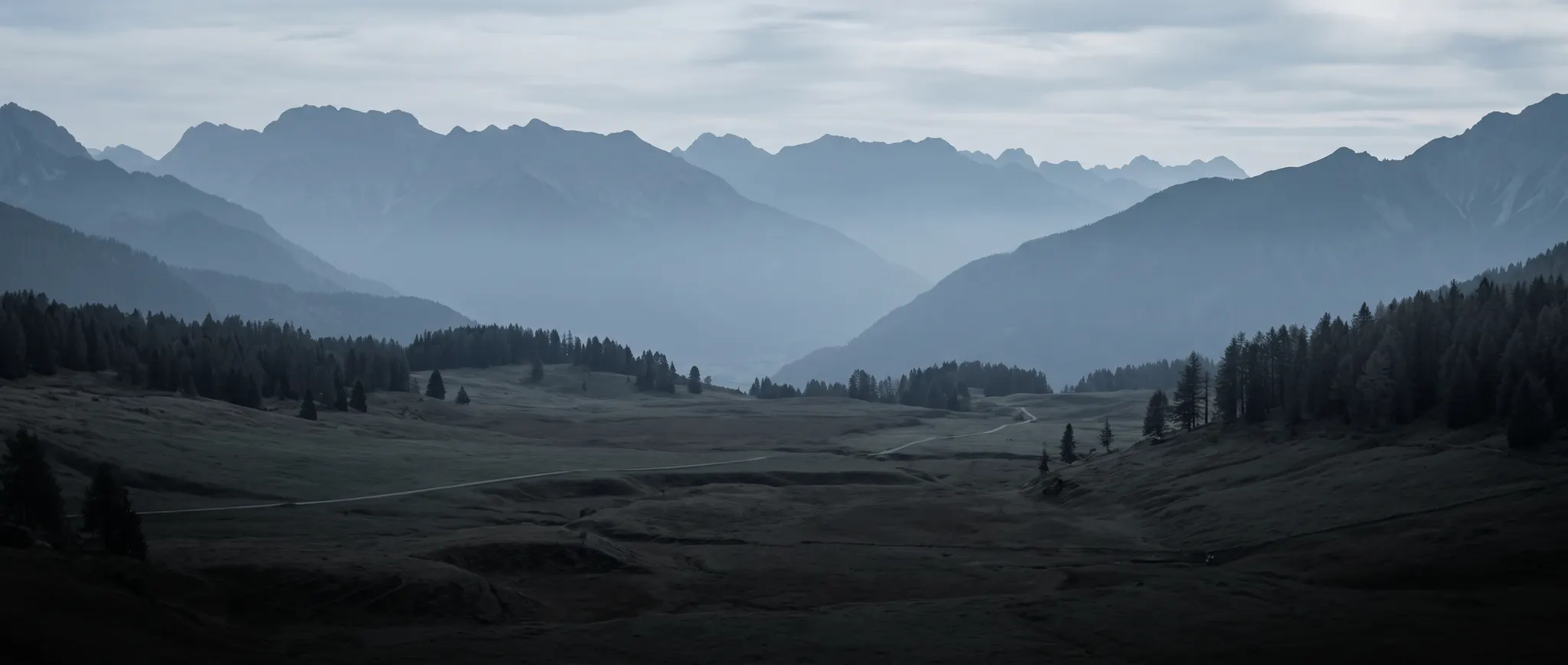 Layered alpine mountain ranges overlooking a quiet valley