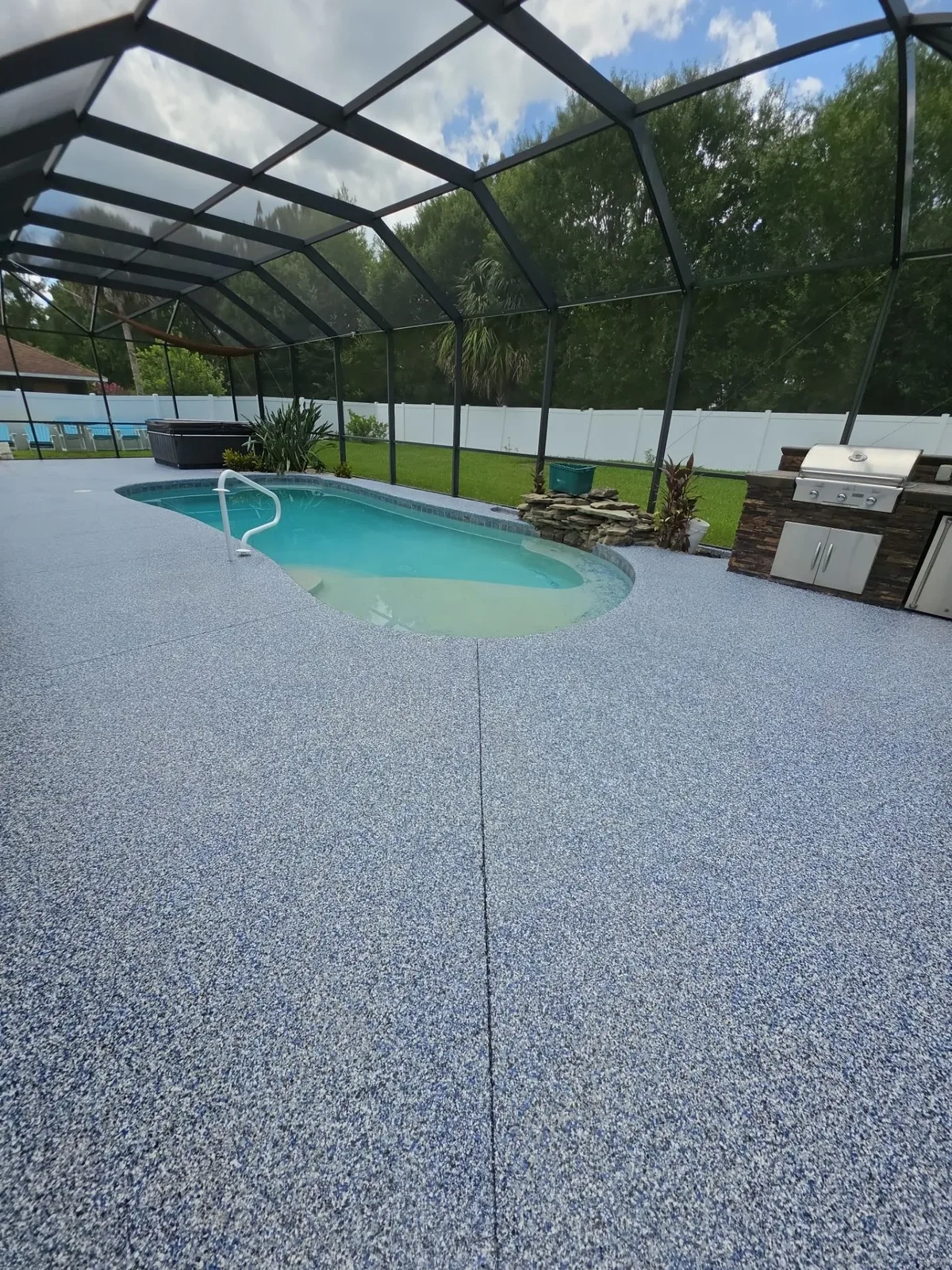 Finished blue flake pool deck beside an outdoor kitchen