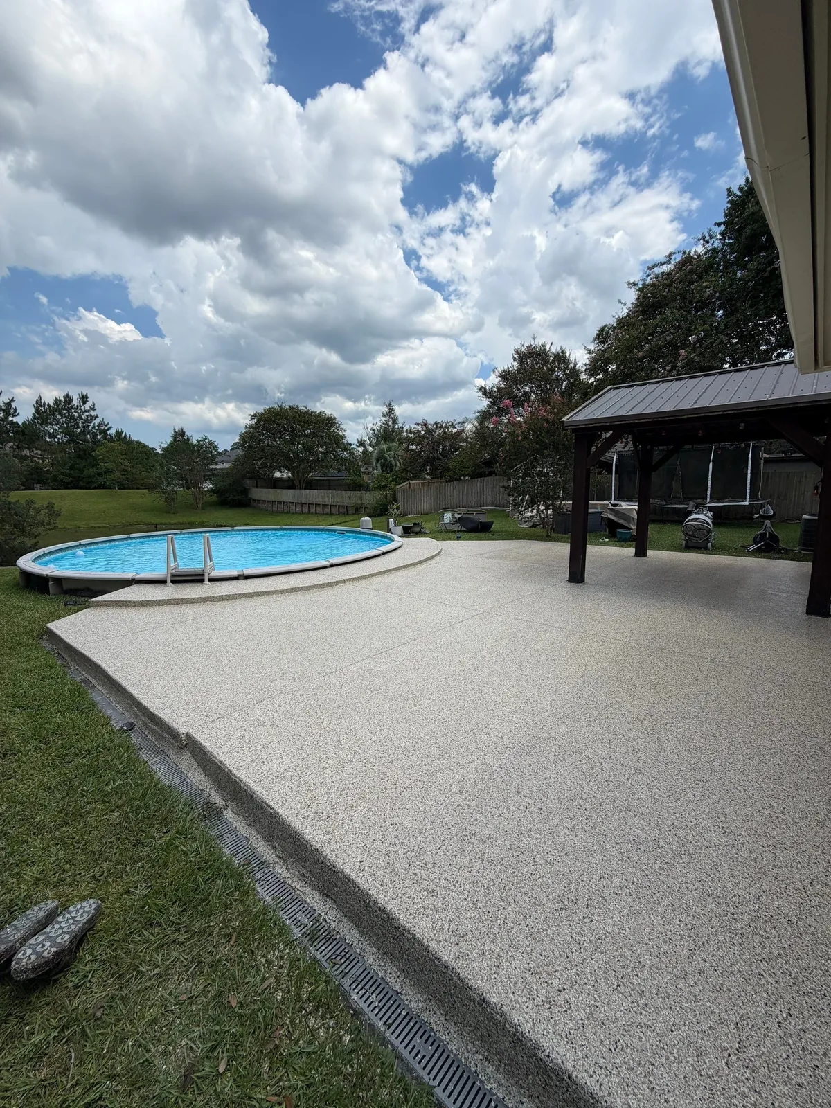 Finished textured coating on a backyard patio beside a pool and gazebo