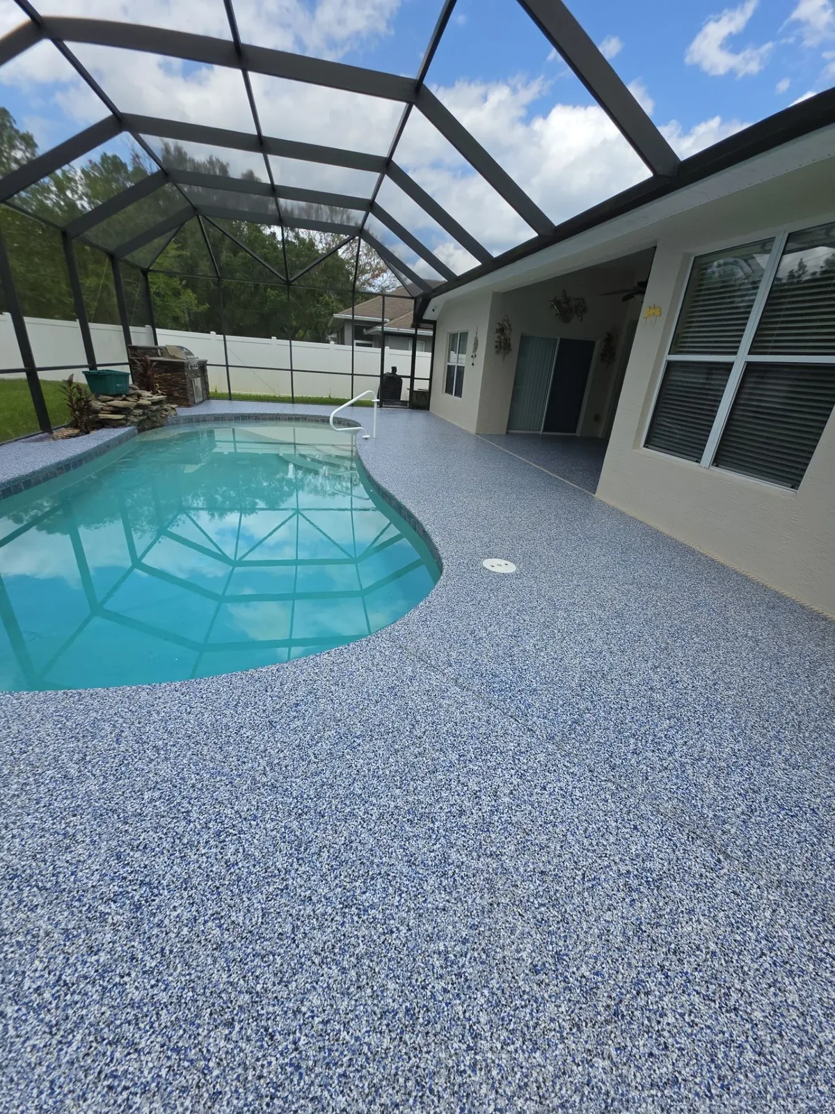 Blue flake pool deck coating installed around a screened residential pool