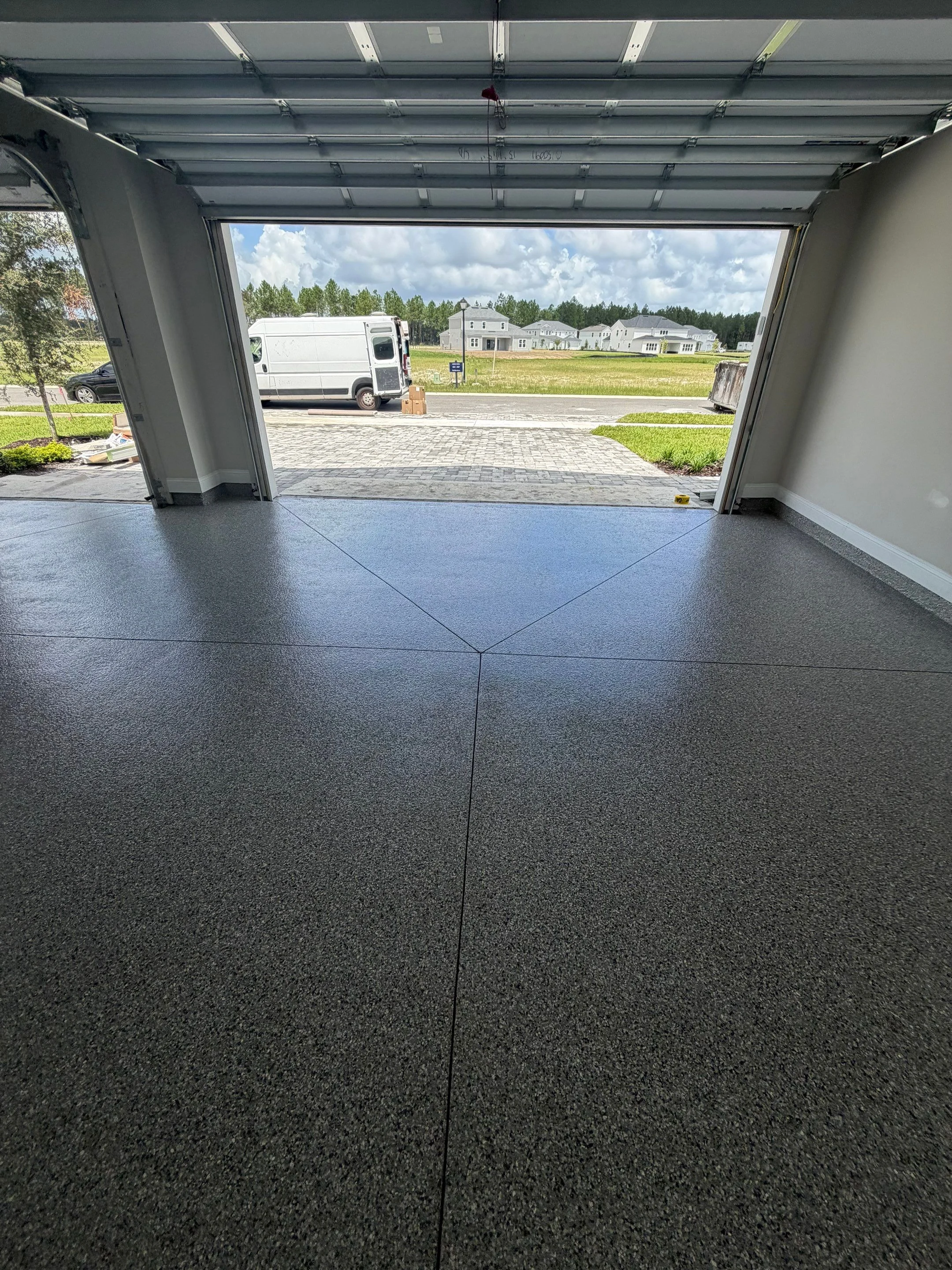 Finished grey flake garage floor viewed toward the driveway