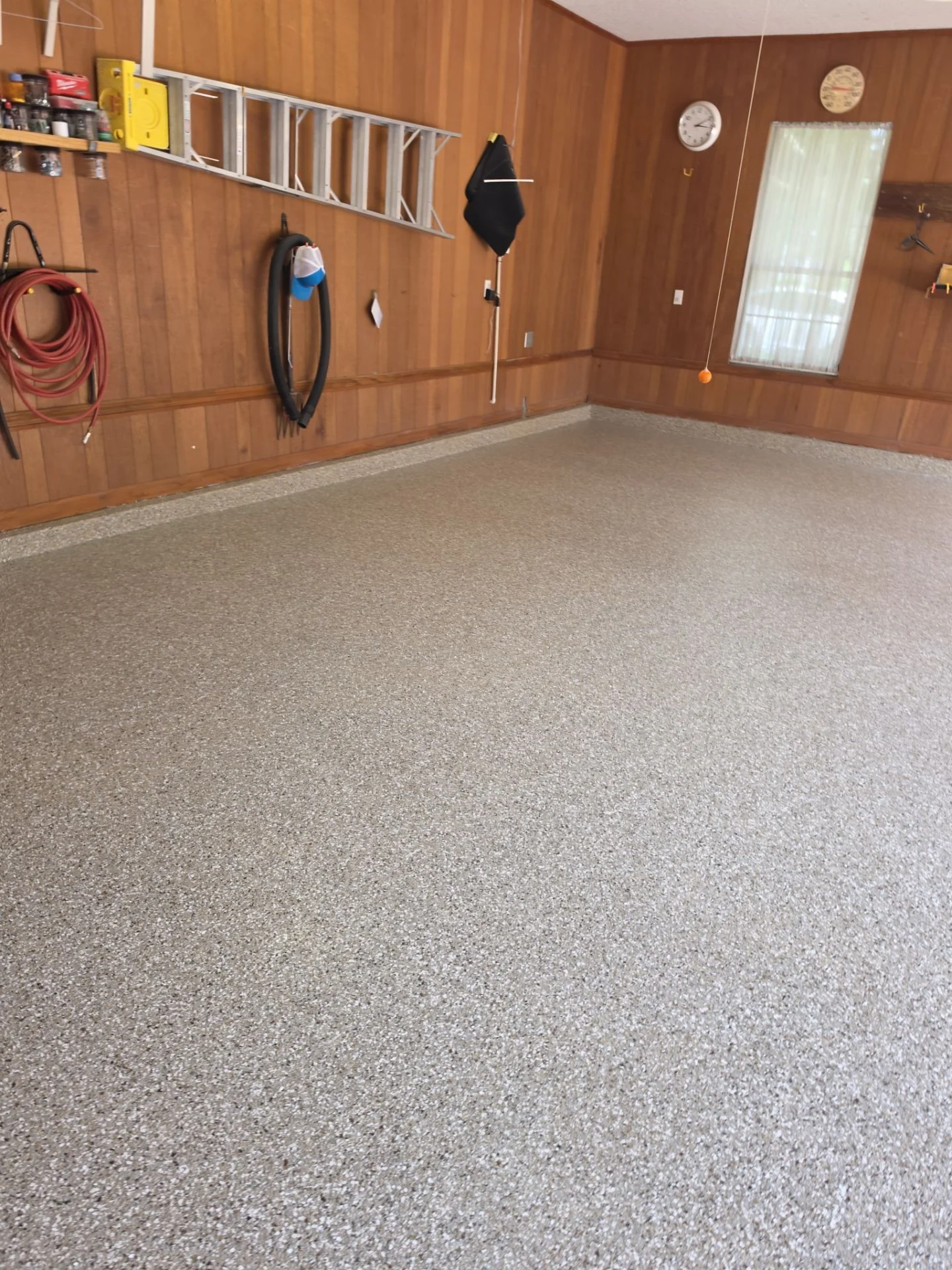 Finished grey flake coating in the same wood-paneled garage