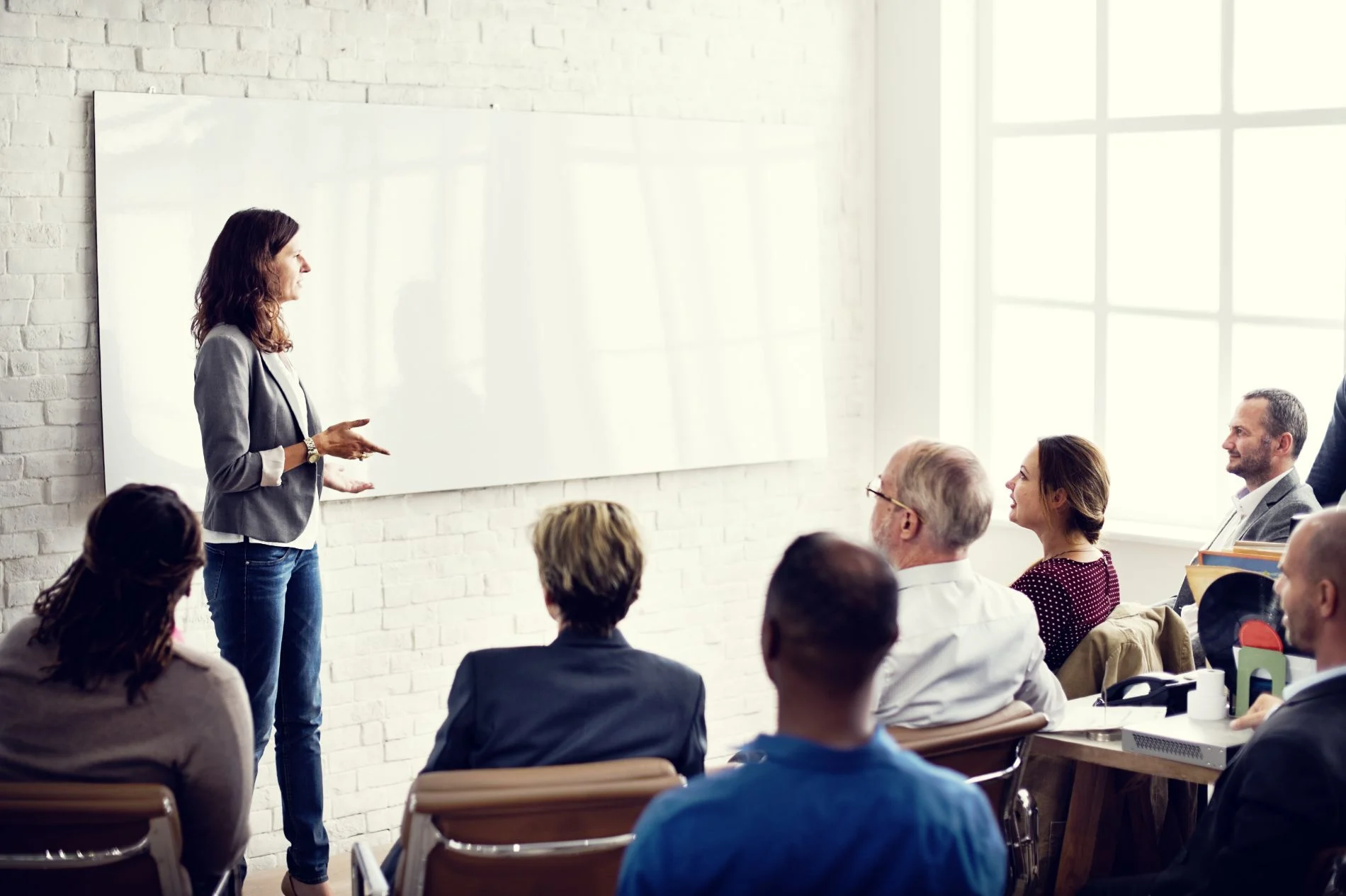 A facilitator leads a workshop for a seated team in a bright office