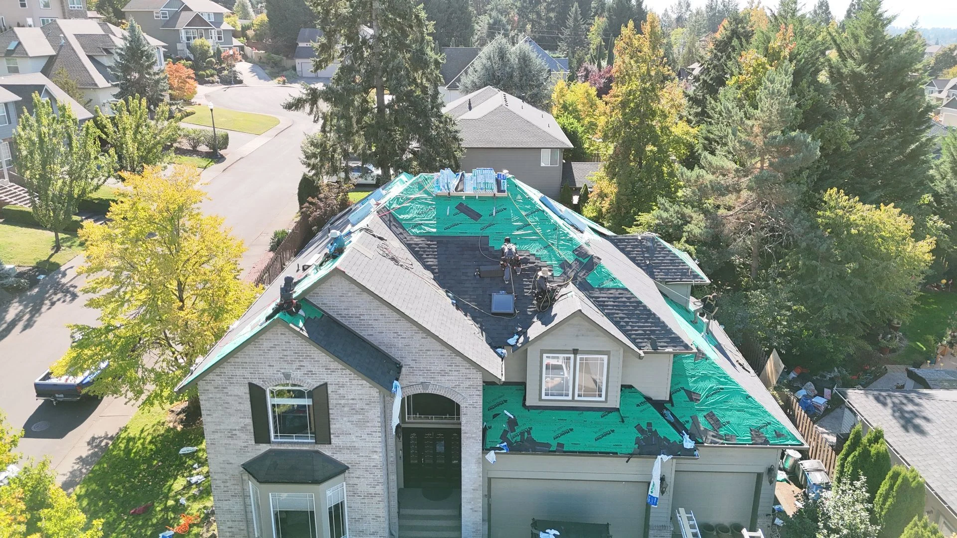 Aerial view of a home during roof repair, with shingles removed down to the underlayment