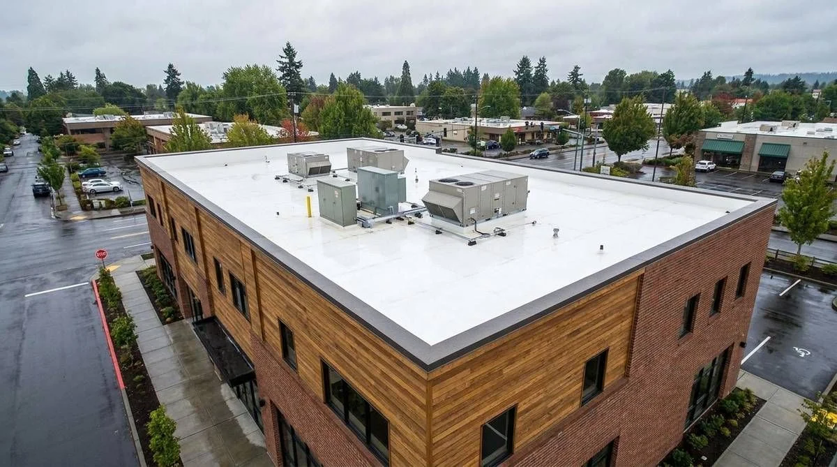 Aerial view of a commercial building with a white flat roof and rooftop units