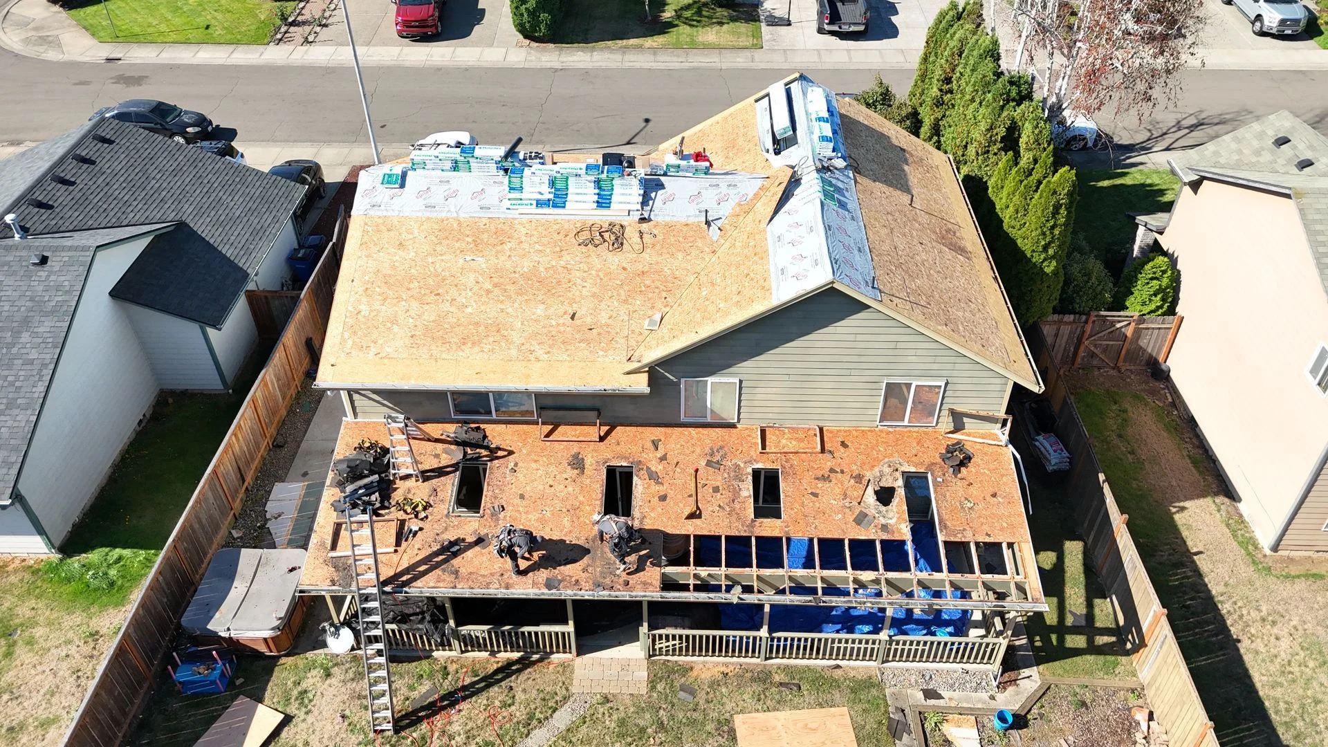 Aerial view of a two-story home during a reroof, with new decking and underlayment going on