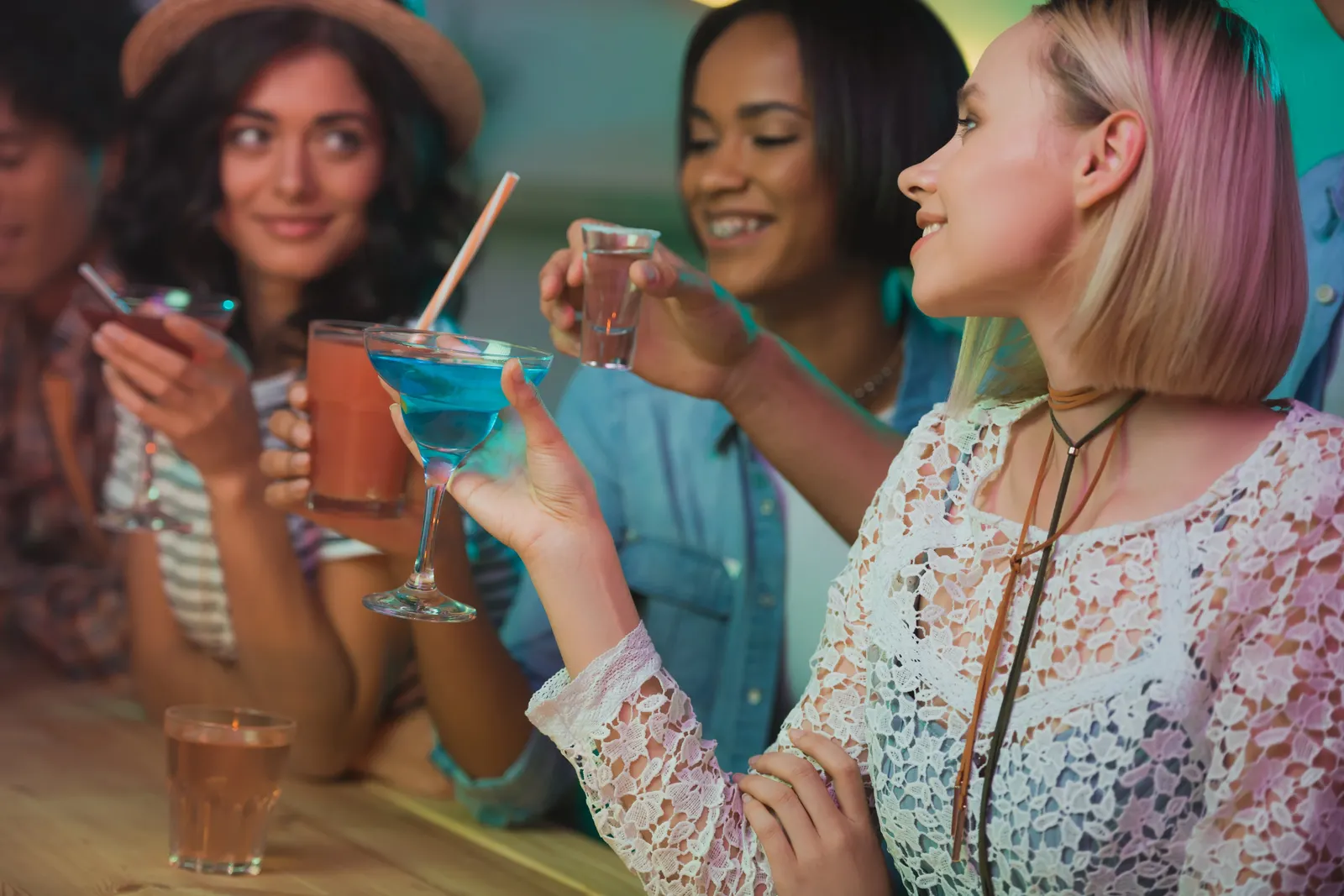 Friends raising cocktails and shots together at a bar