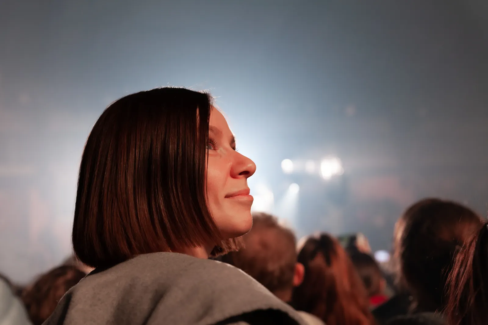 Woman smiling up at the stage lights in a crowd at a live show