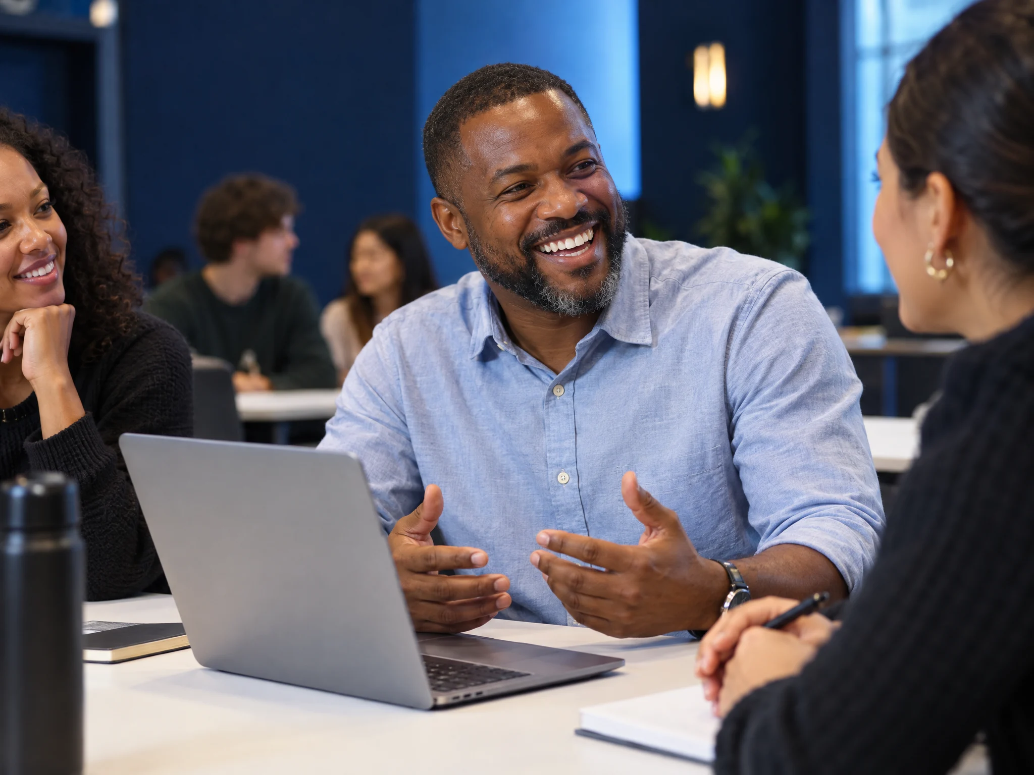 A business owner laughing with classmates at a class table