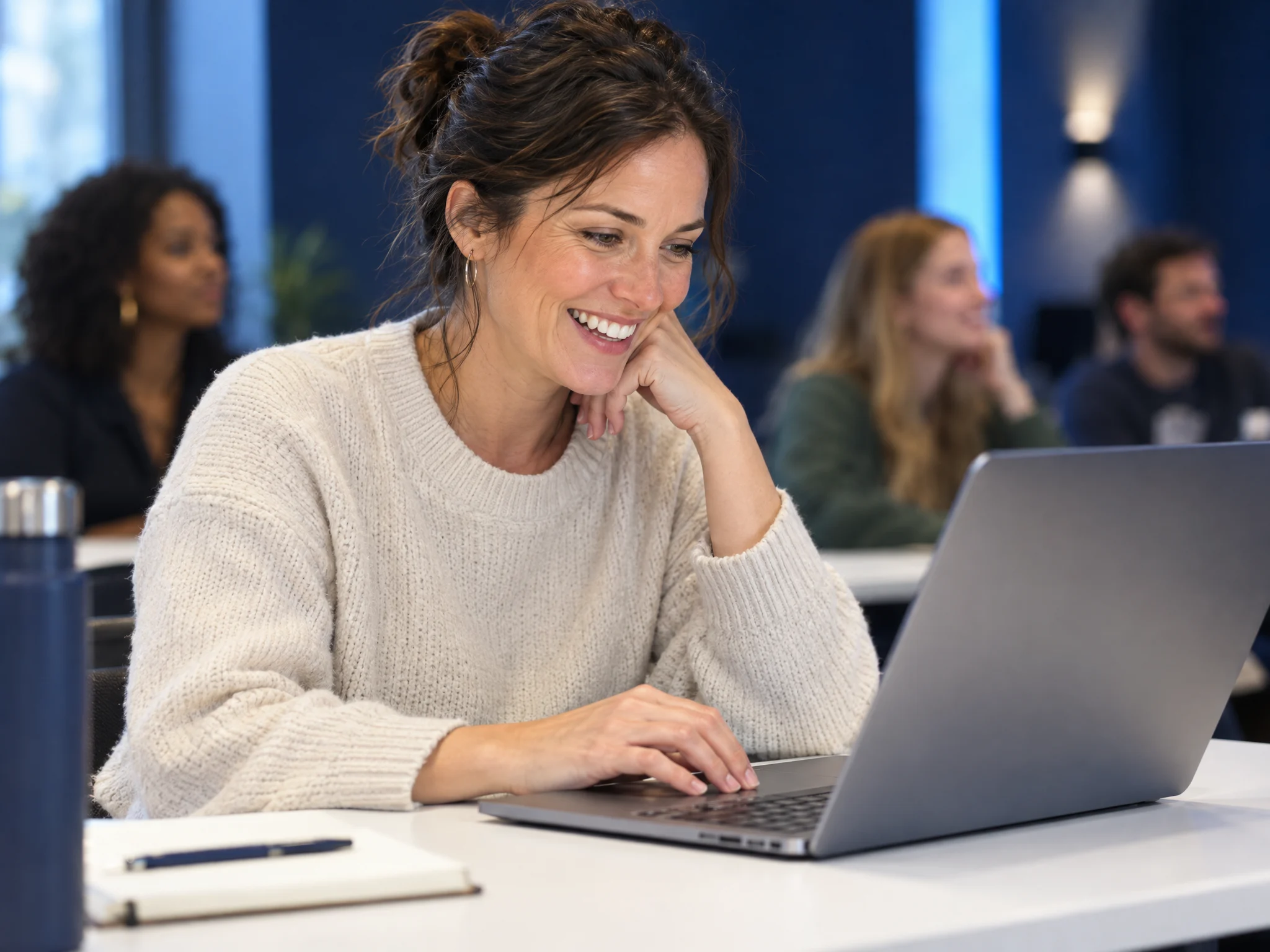 A smiling parent working on a laptop during a class