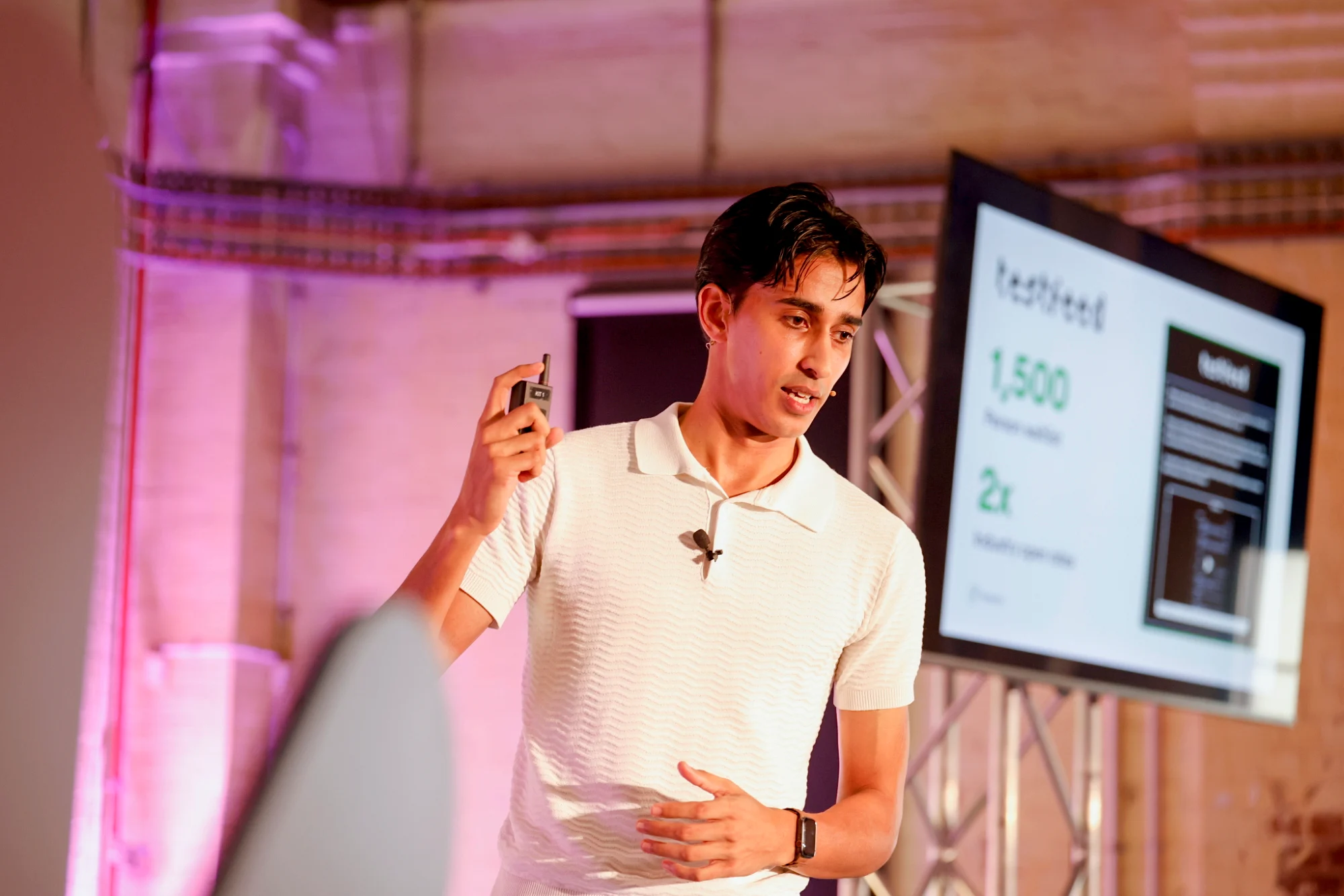 Isaac Peiris speaking on stage in front of a presentation screen
