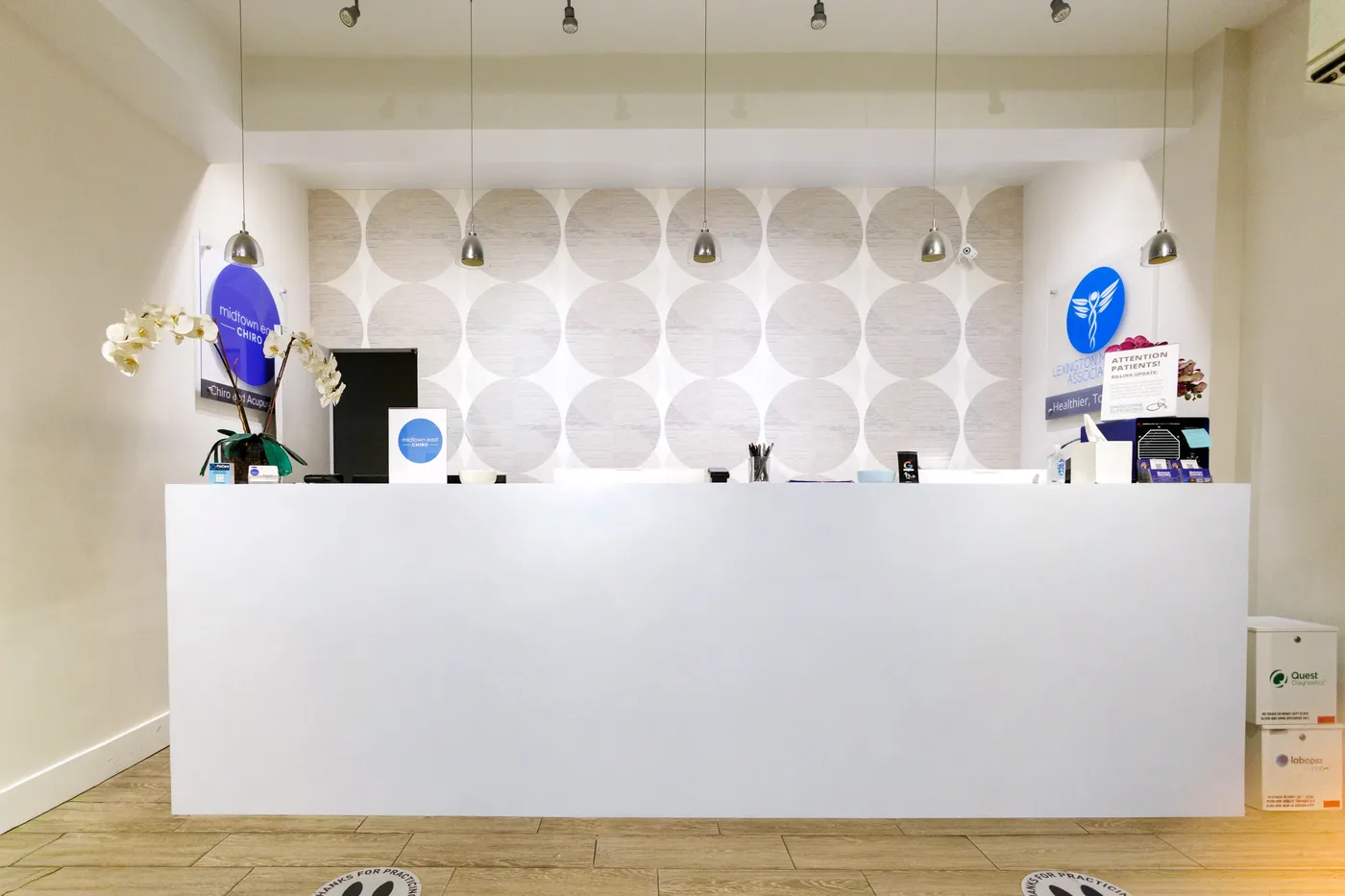 Front desk under pendant lights, with the Midtown East Chiro sign on the left wall