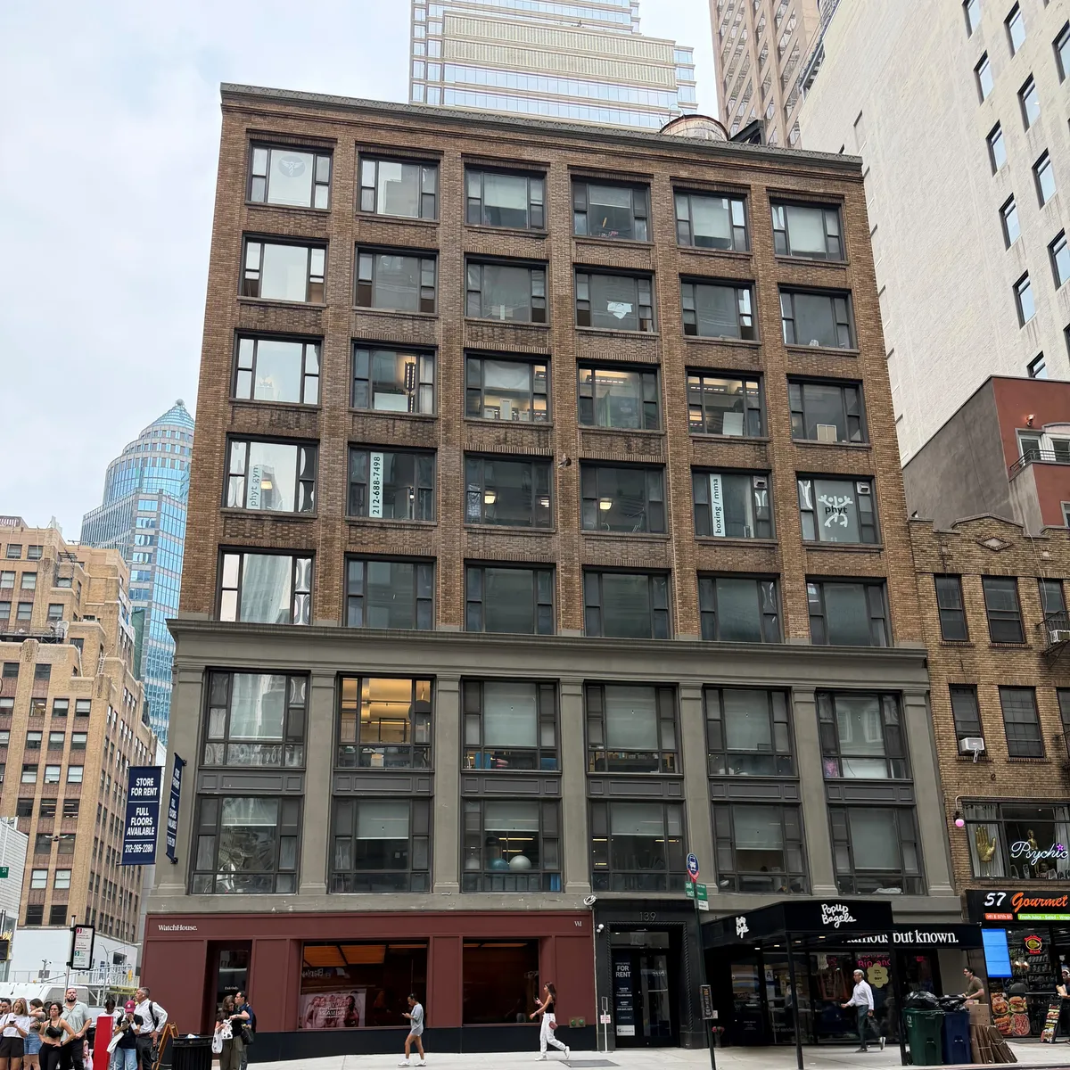 The 139 East 57th Street building, a brown brick building with a stone base, between WatchHouse and Popup Bagels