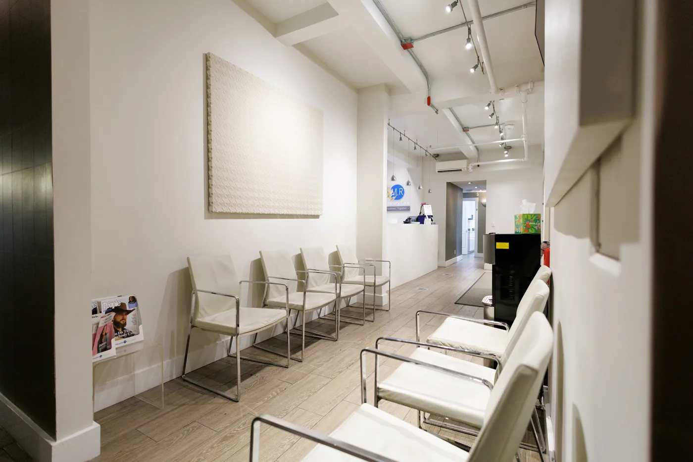 Bright waiting area with white chairs and light wood floors
