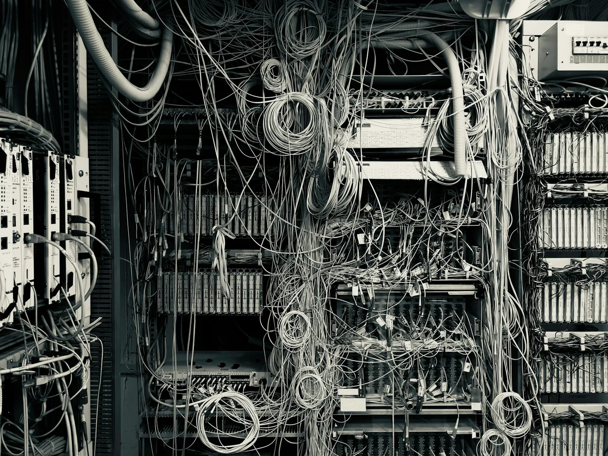 A densely tangled network cabinet filled with overlapping cables and accumulated connections