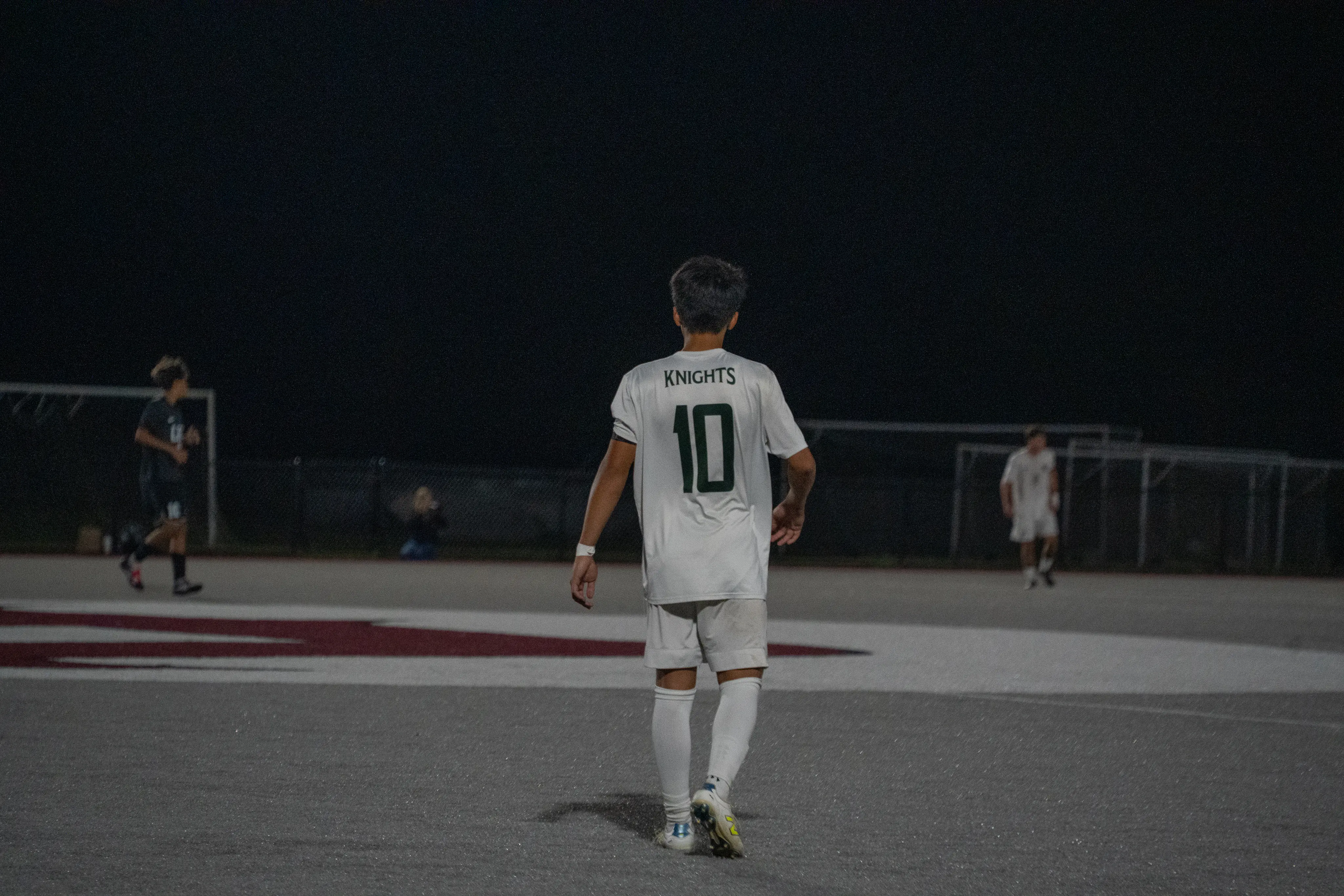 Soccer player number 10 watching play during a night match