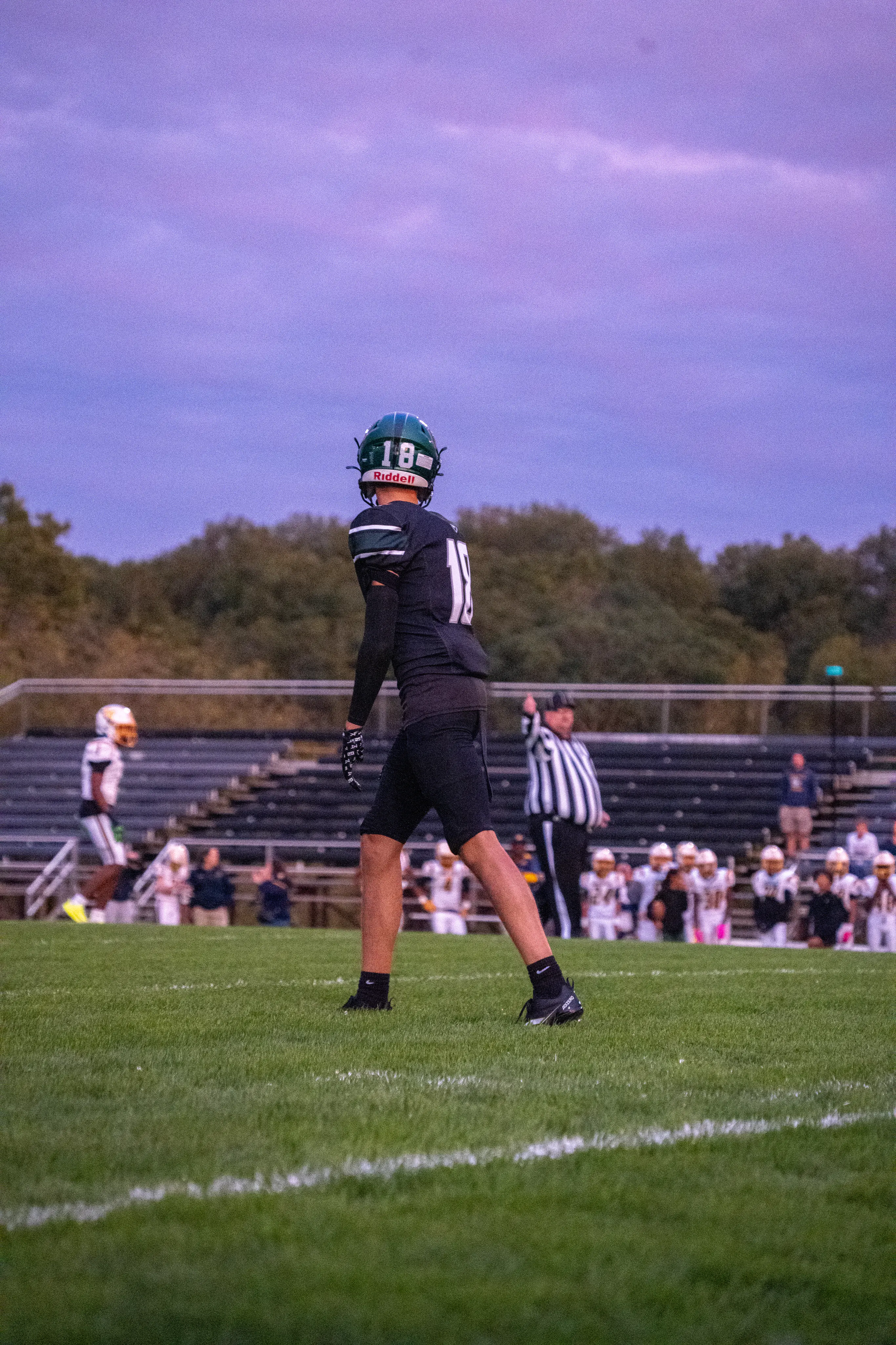 Football player number 18 on the field under an evening sky