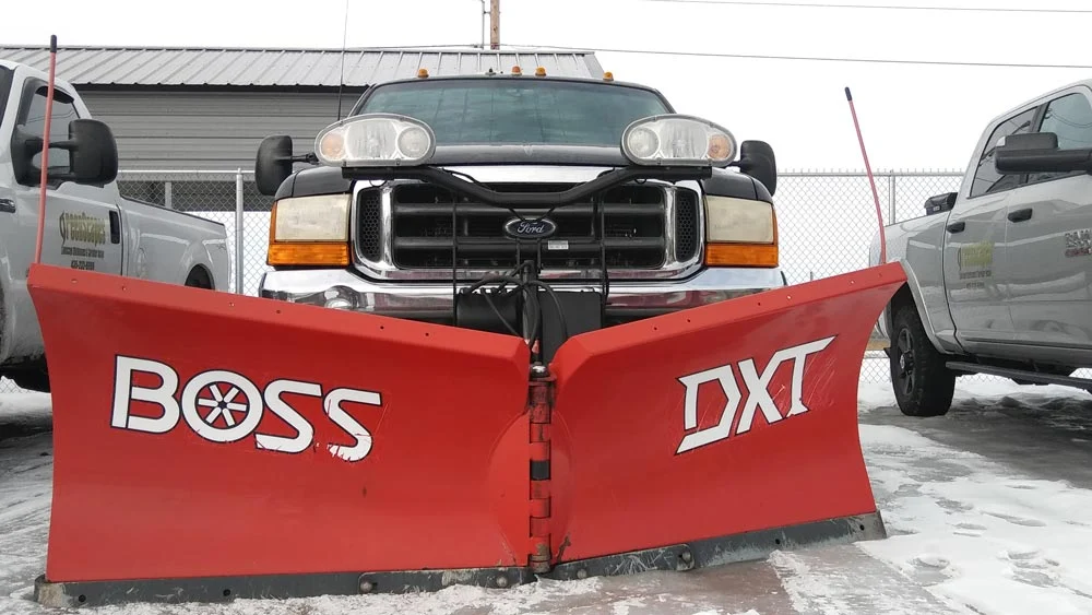 Red BOSS snow plow mounted on a Greenscapes work truck
