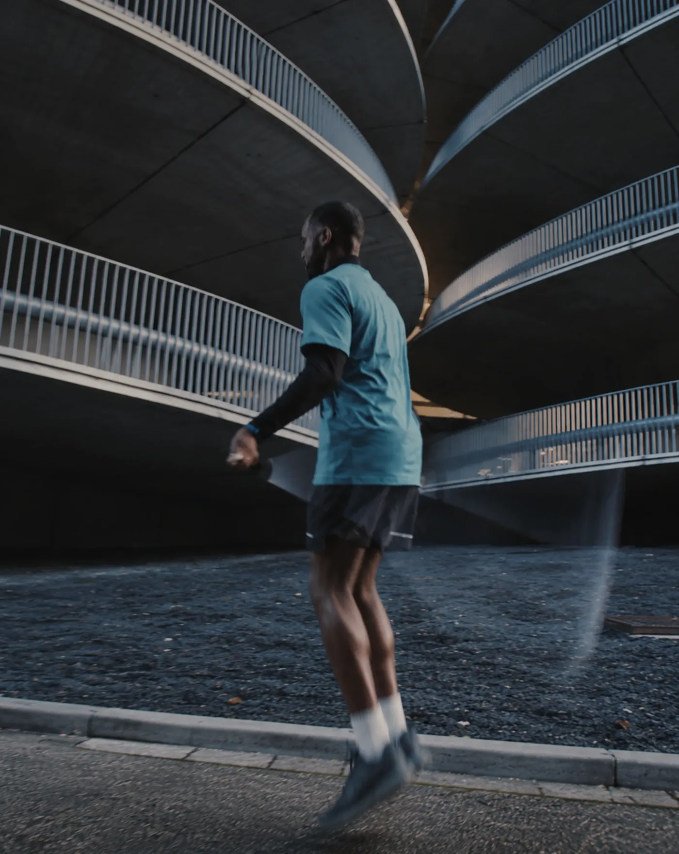 An athlete jumps rope beneath spiral concrete ramps at dusk.
