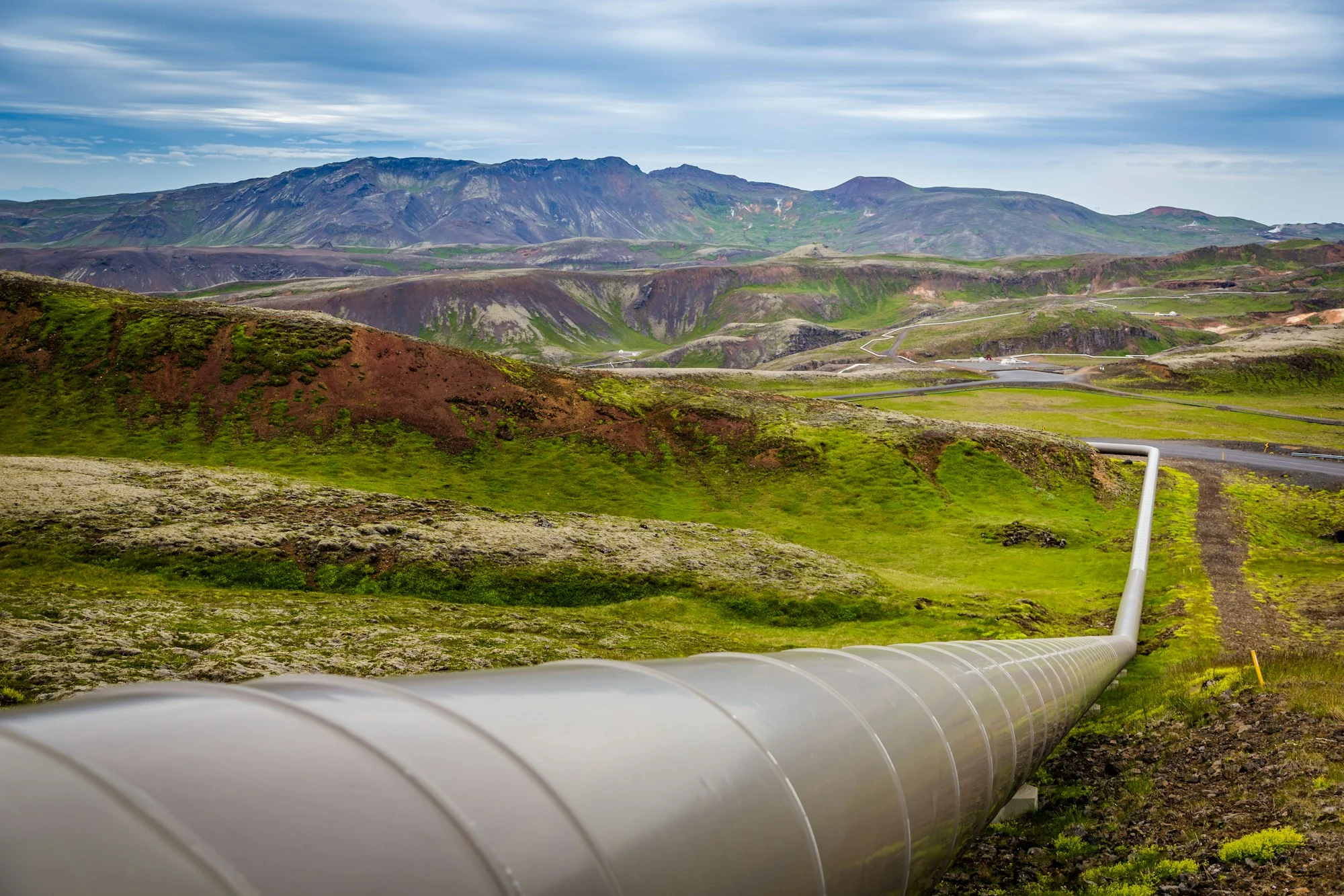 An above-ground pipeline running across green hills