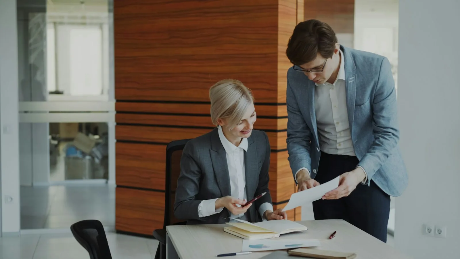 Two colleagues reviewing printed documents together at an office desk